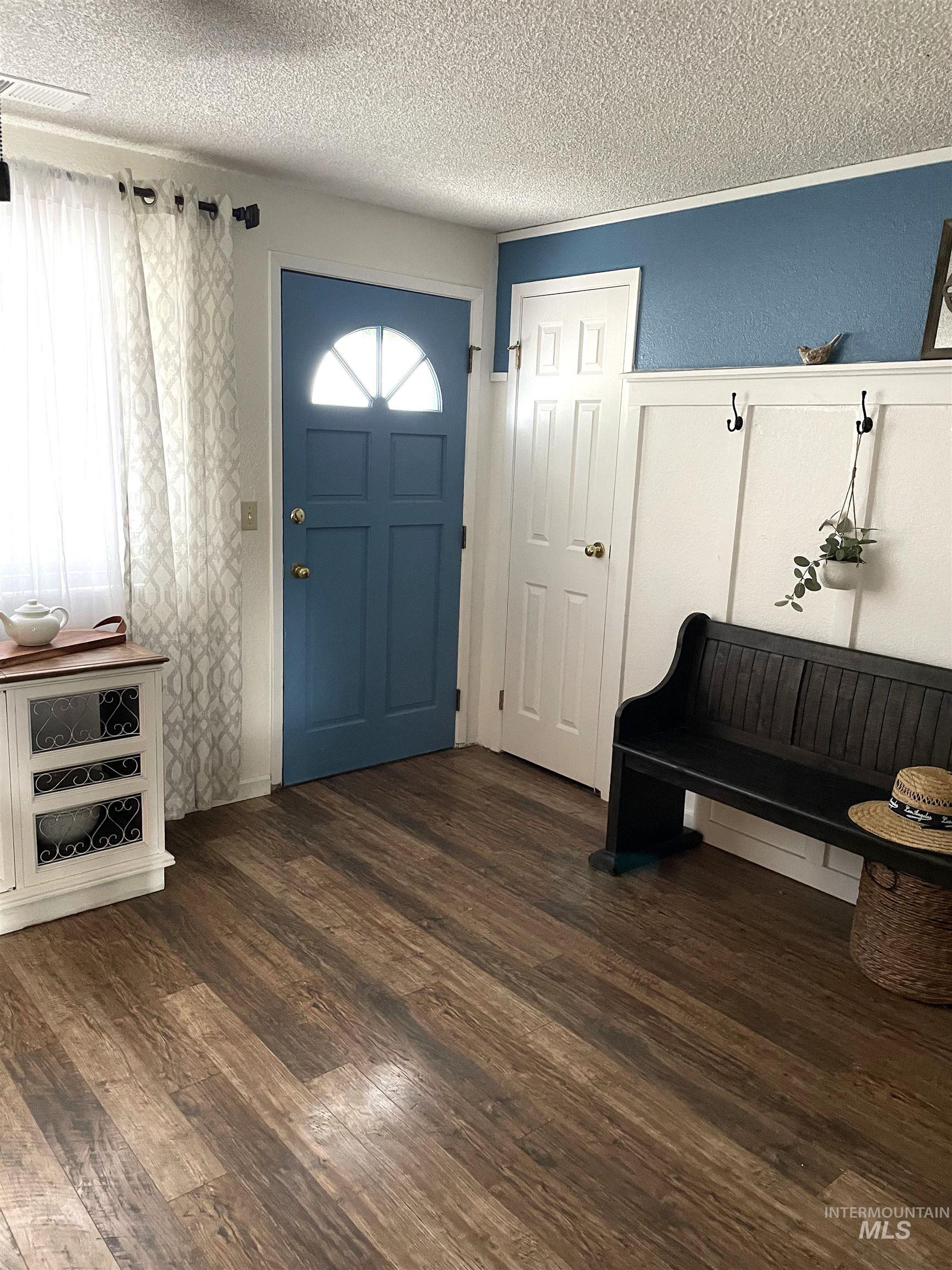 Foyer entrance featuring dark wood-style flooring and a textured ceiling