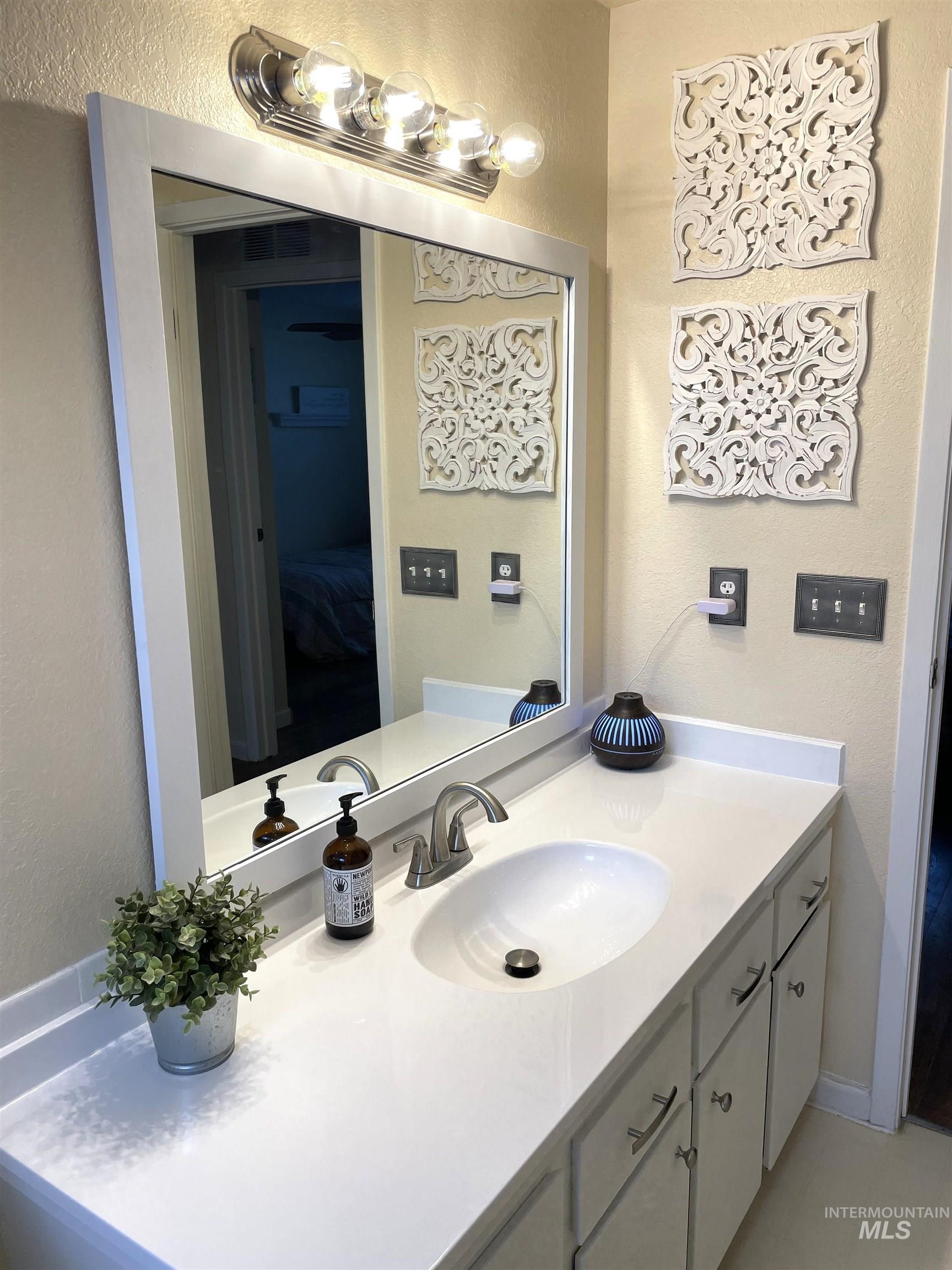 Bathroom with a textured wall and vanity