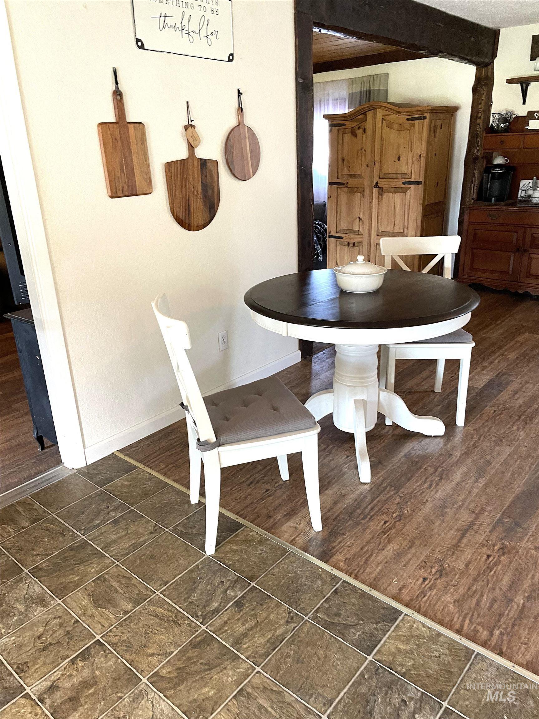 Dining room featuring dark wood-style flooring and beamed ceiling