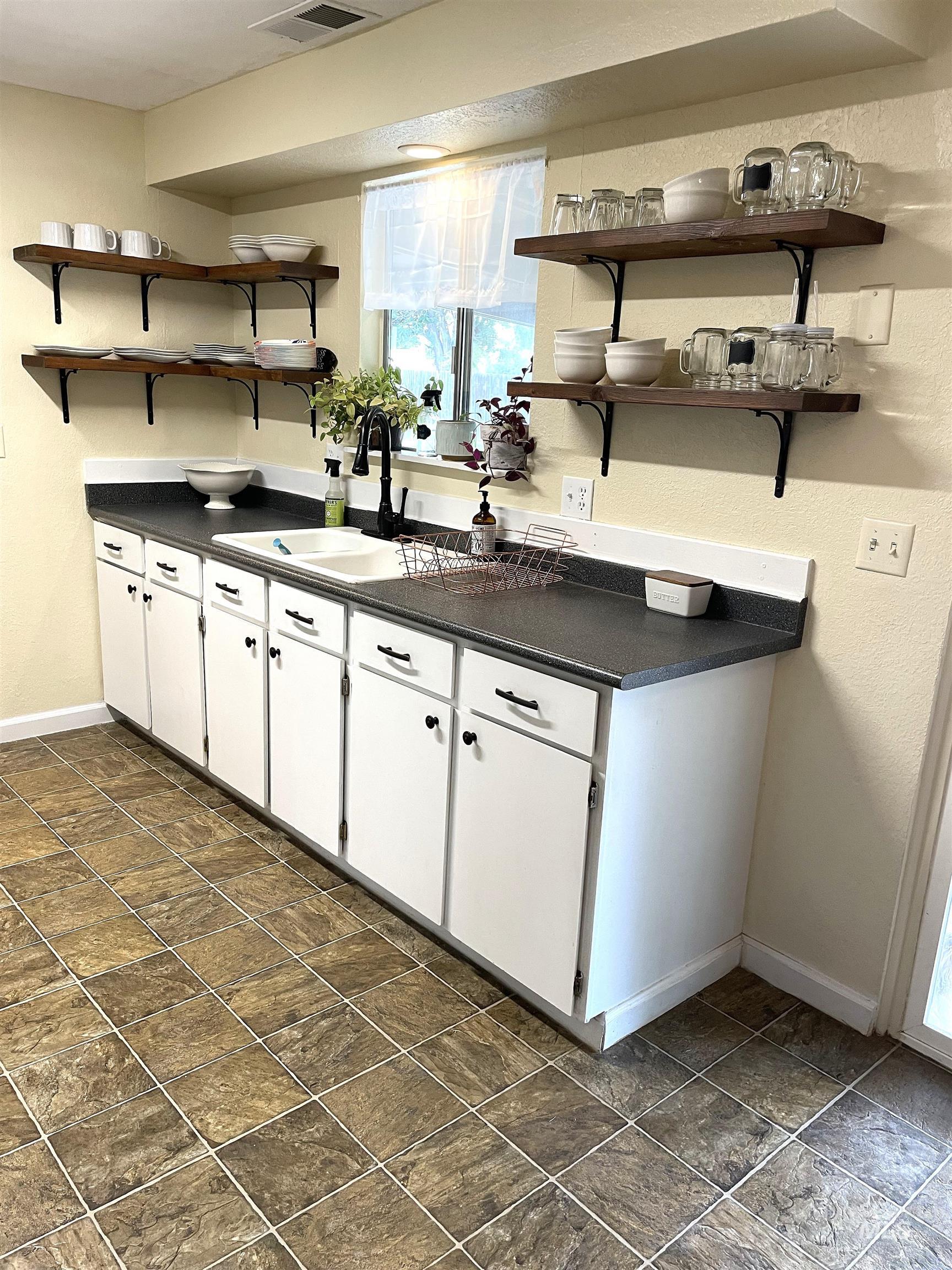 Kitchen featuring open shelves, dark countertops, and white cabinets