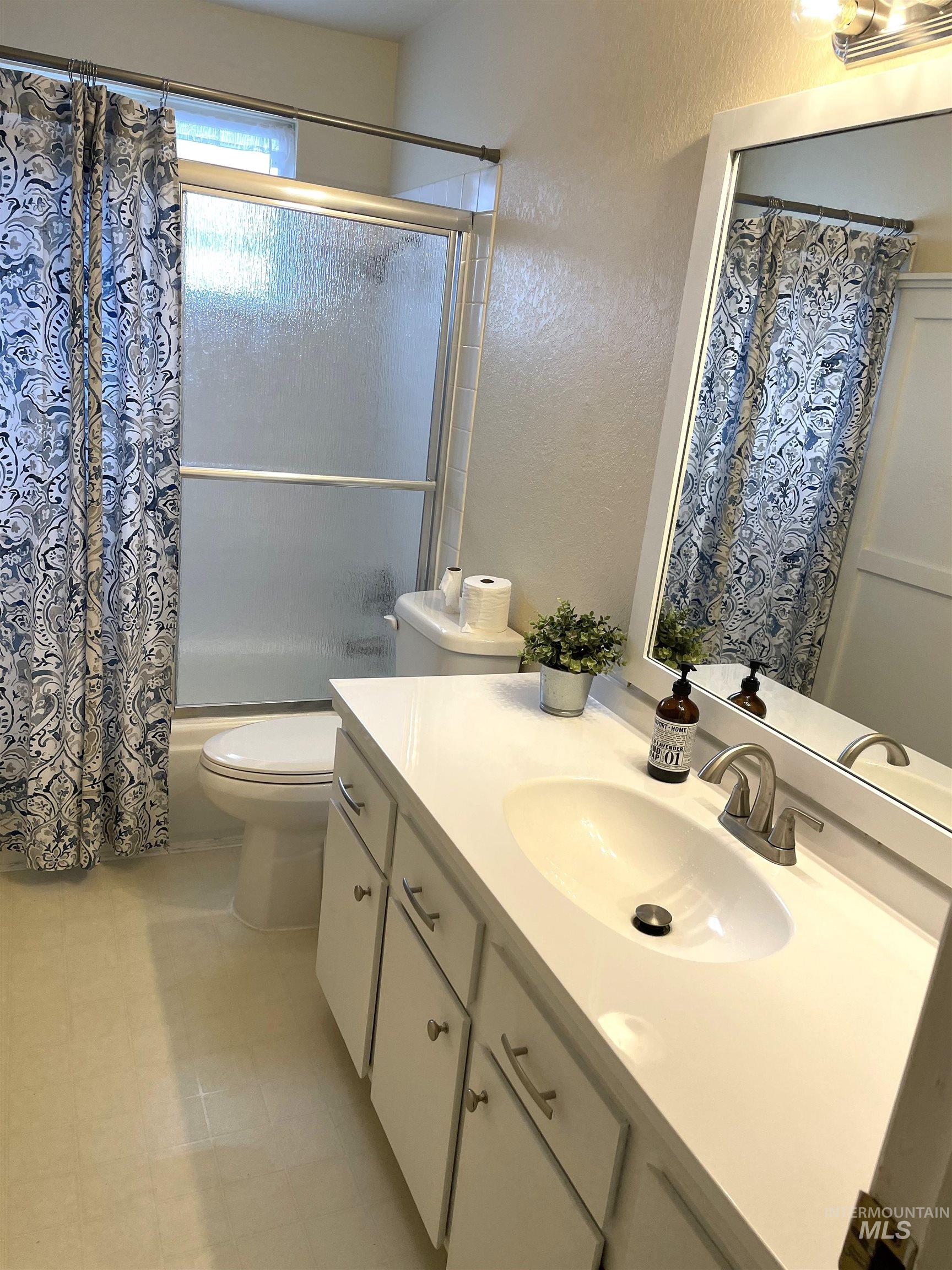 Bathroom featuring a textured wall, shower / bath combo with shower curtain, and vanity
