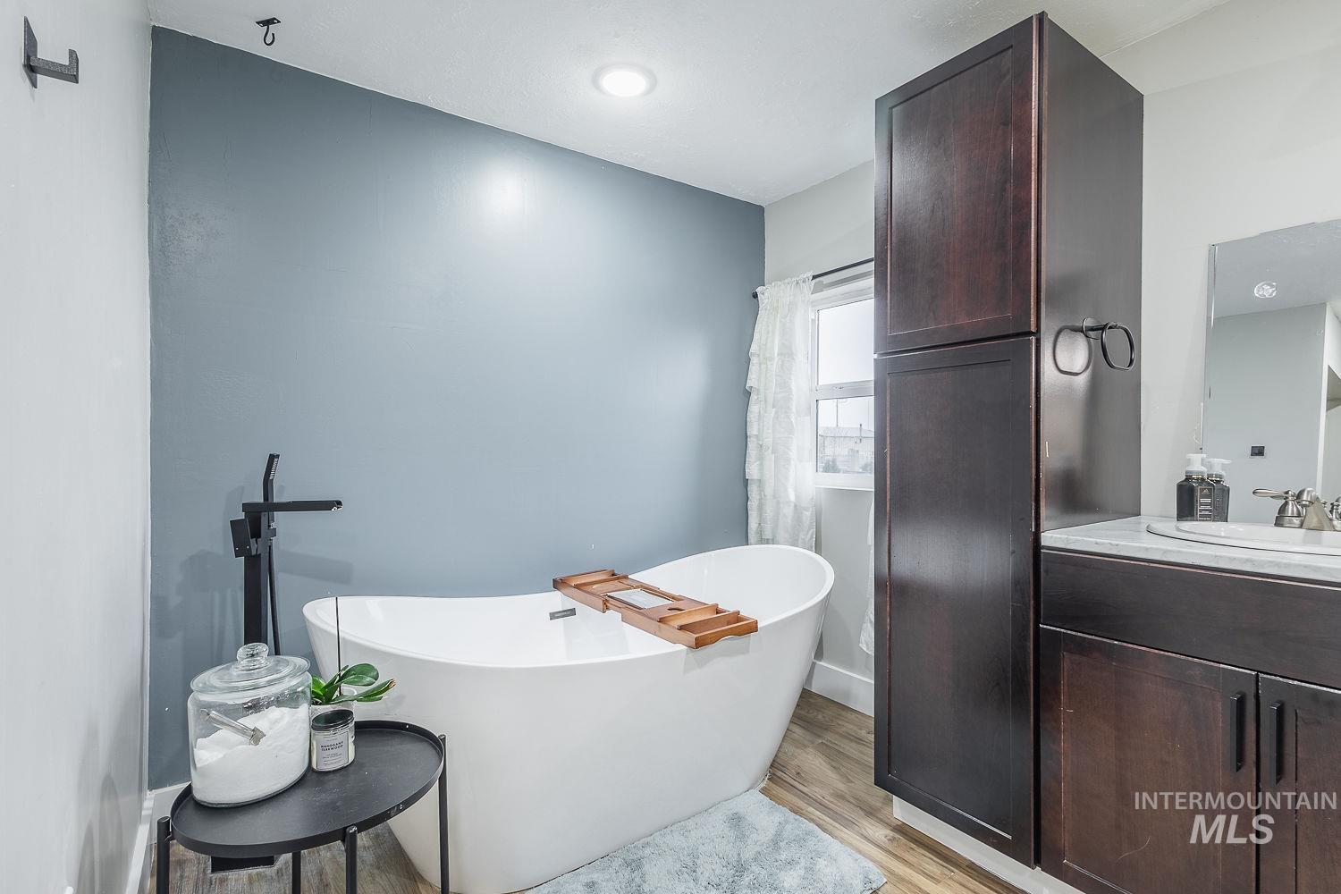 Bathroom featuring vanity, a soaking tub, and light wood finished floors