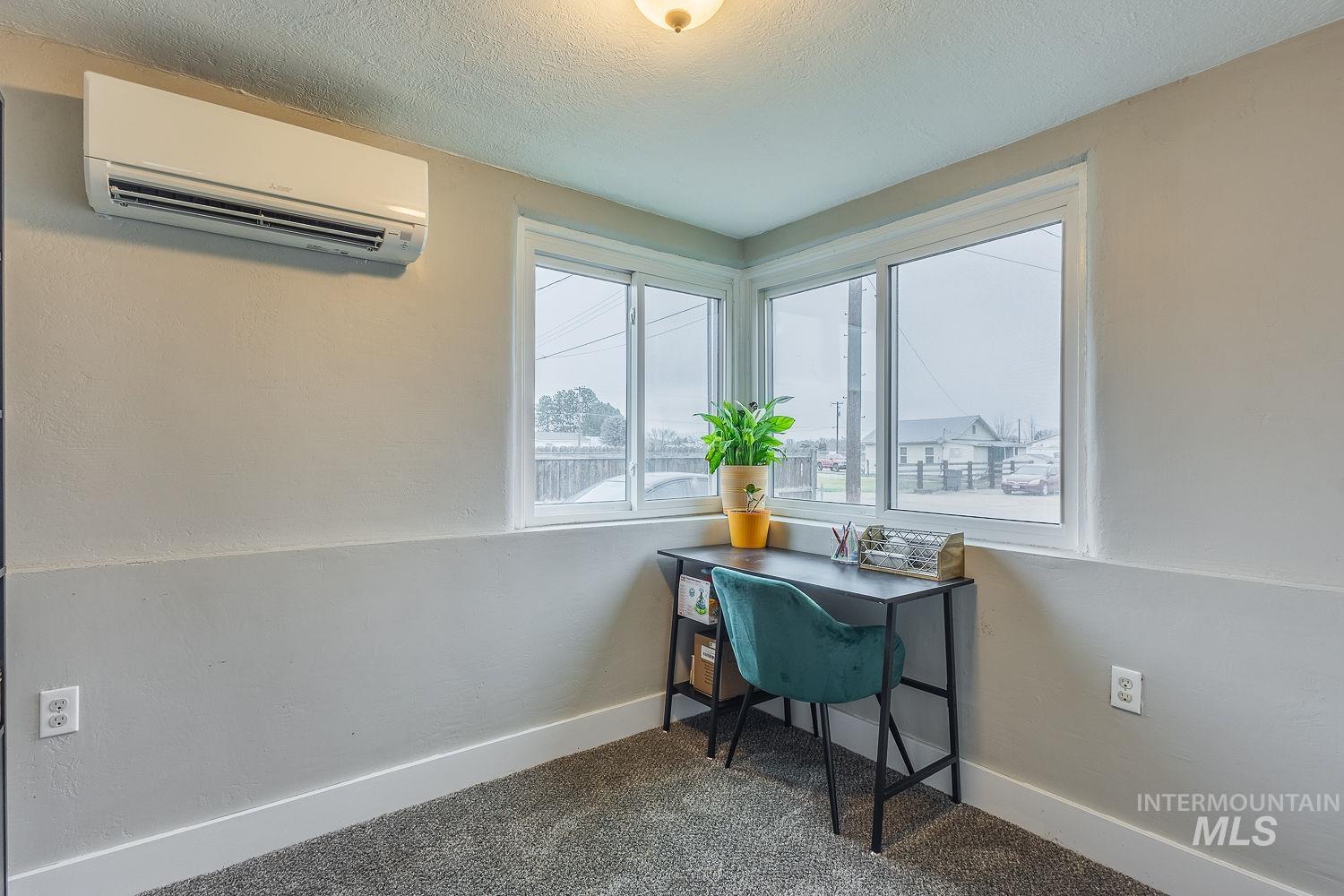 Office area featuring an AC wall unit, a textured ceiling, and carpet