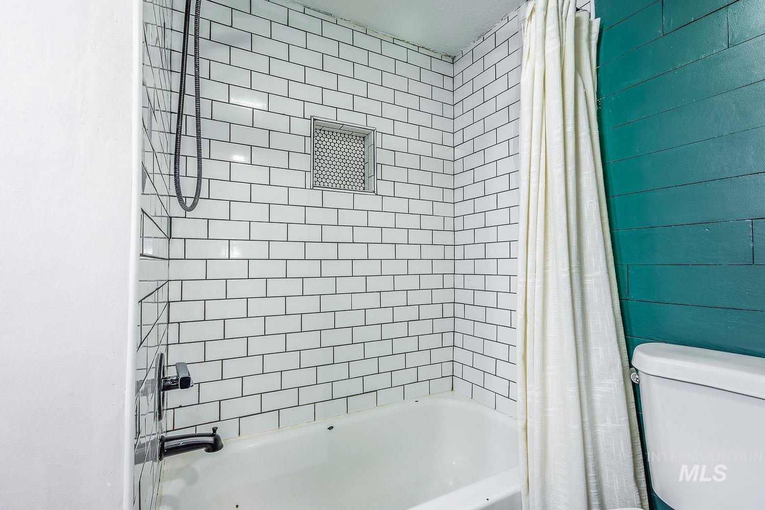 Bathroom featuring shower / tub combo with curtain and toilet