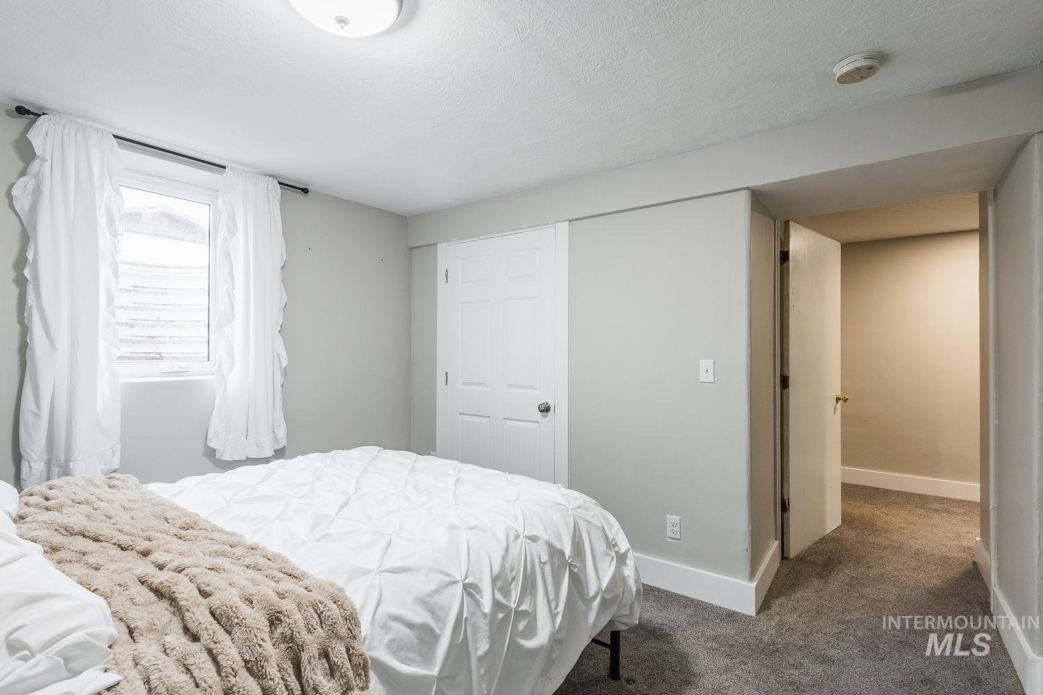 Bedroom with dark carpet, a textured ceiling, and a closet
