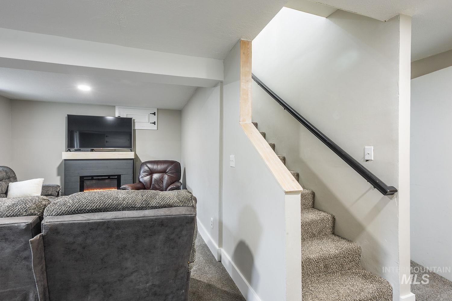 Living area featuring carpet flooring, stairway, and a glass covered fireplace