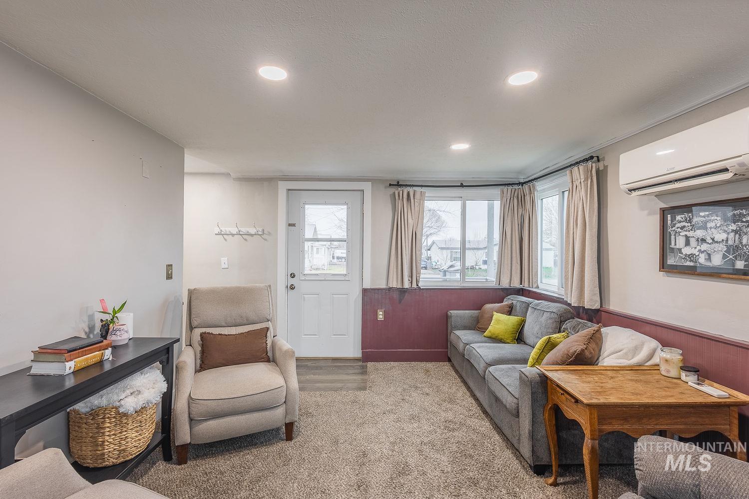 Carpeted living room featuring a wall mounted air conditioner and recessed lighting