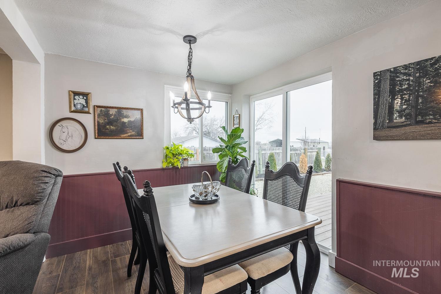 Dining area featuring a wainscoted wall, a chandelier, wood finished floors, and a textured ceiling