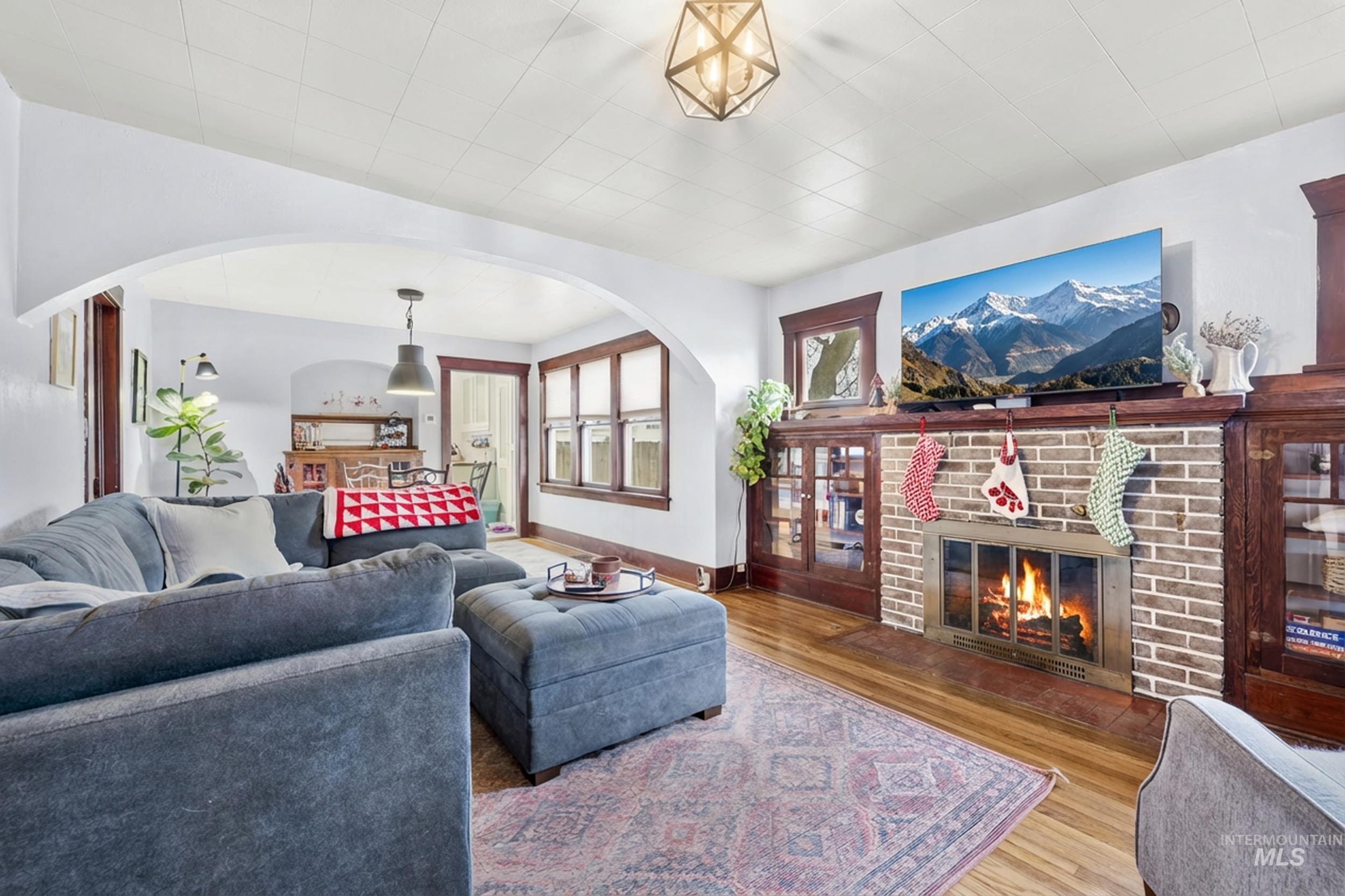 Living room featuring arched walkways, wood finished floors, and a brick fireplace