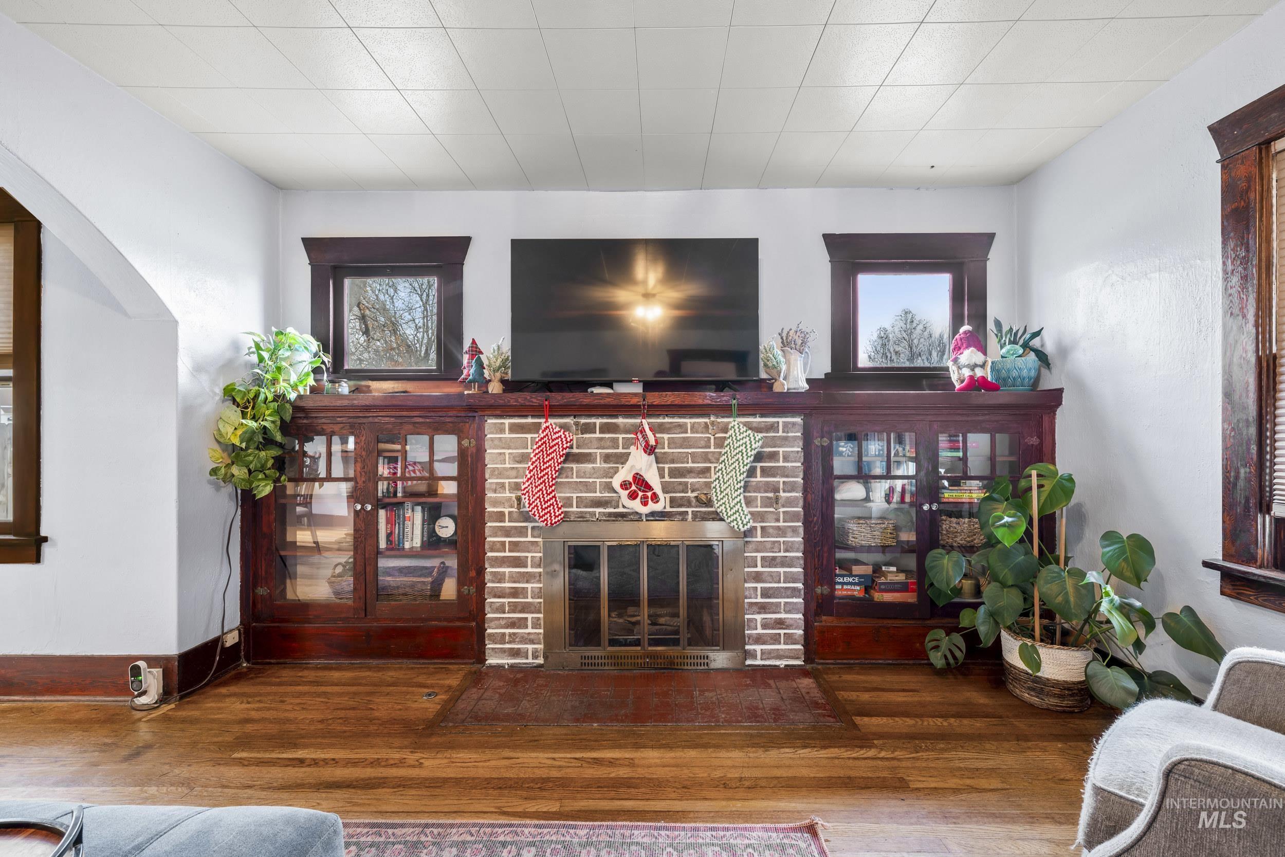 Living room with wood finished floors, a fireplace, and arched walkways