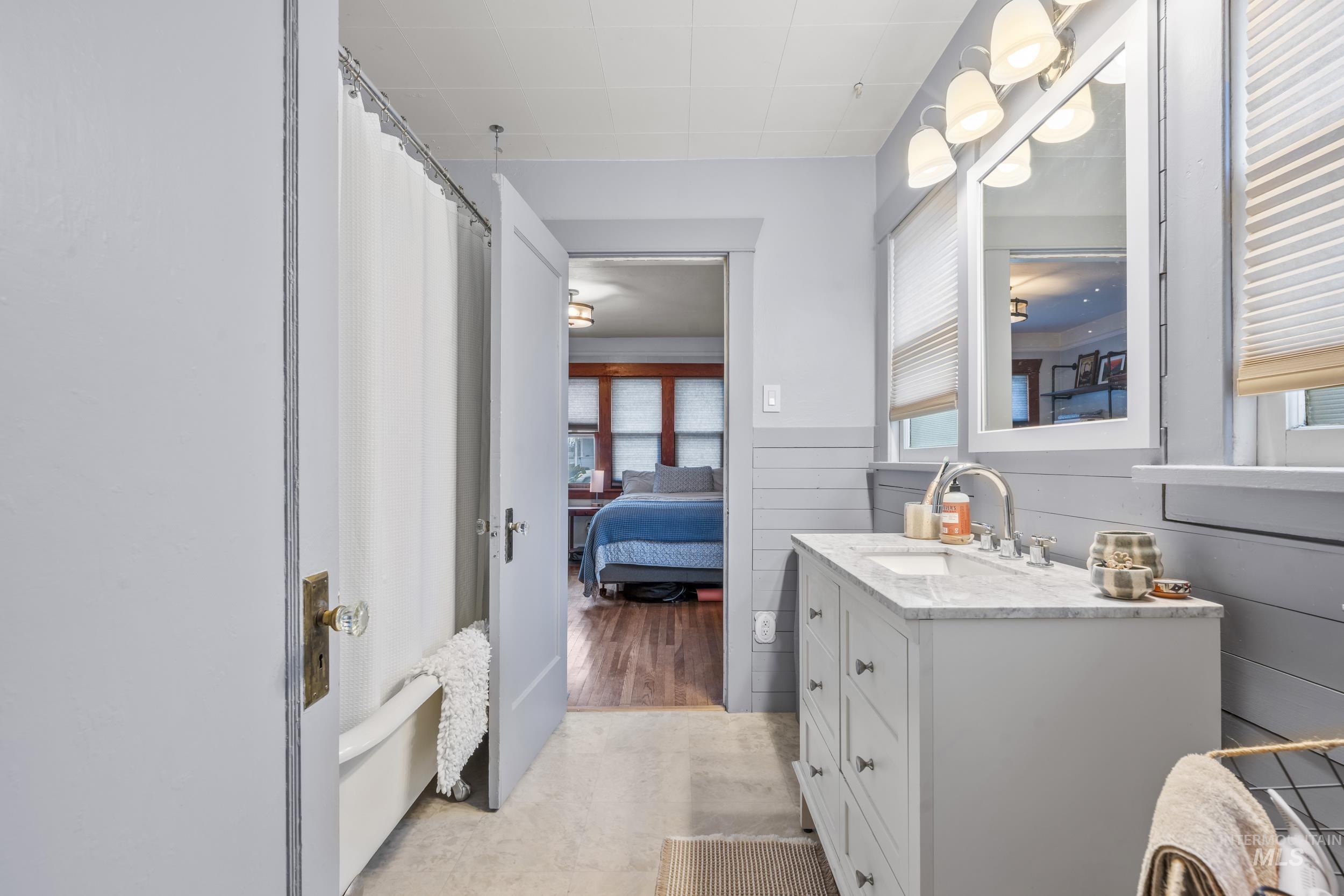 Bathroom featuring vanity, connected bathroom, a shower with shower curtain, and a wainscoted wall