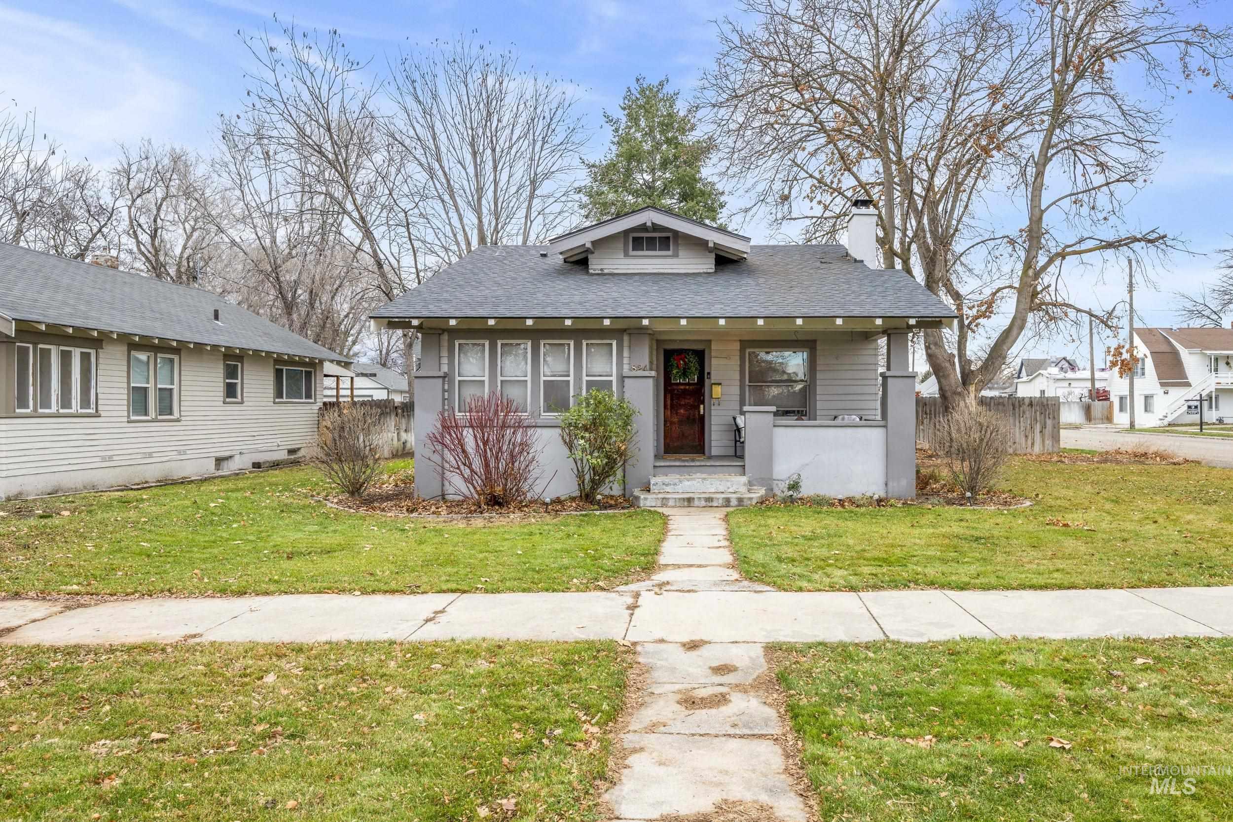 Bungalow-style house featuring a chimney, a shingled roof, and a porch