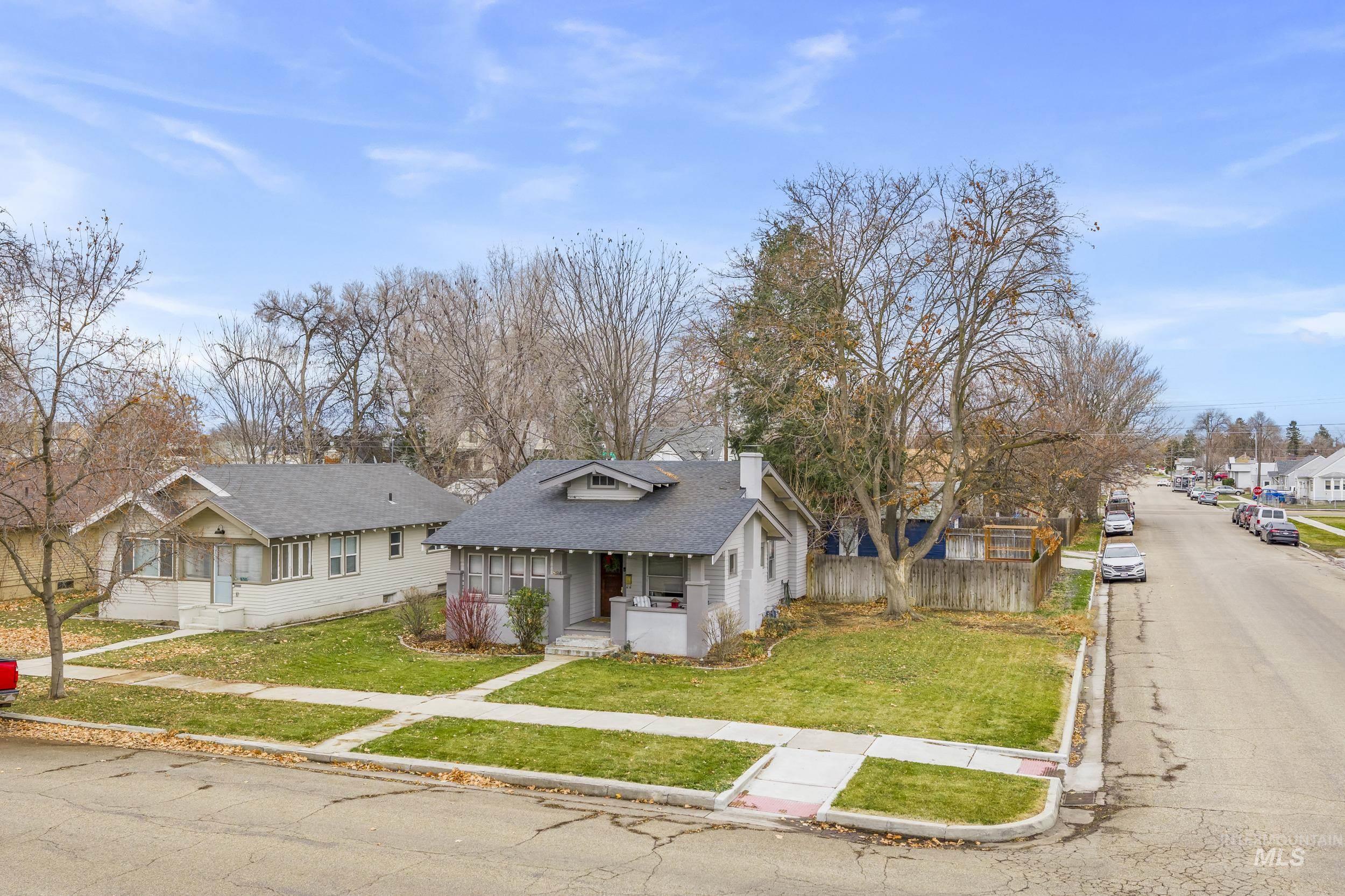 Bungalow-style home featuring a residential view, a chimney, a porch, and a shingled roof