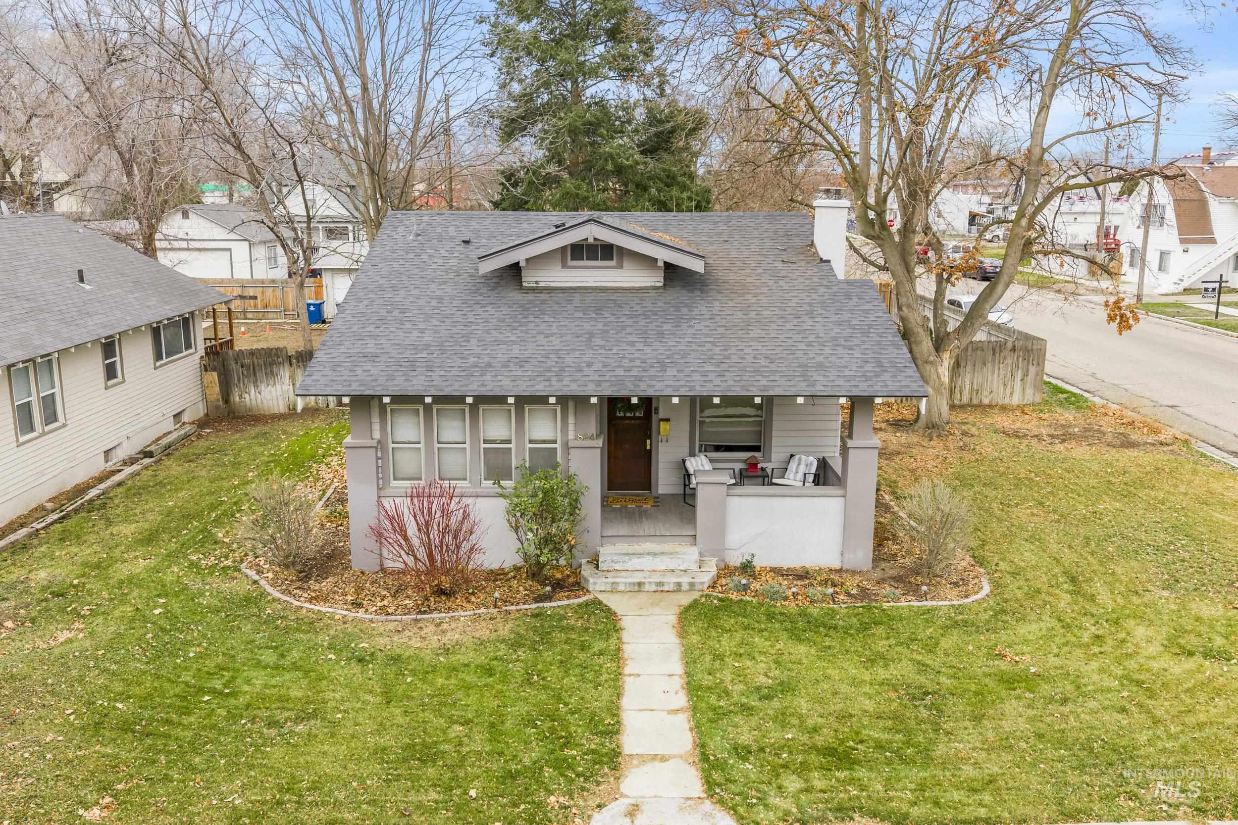 Bungalow-style house featuring roof with shingles, a porch, a chimney, and a residential view