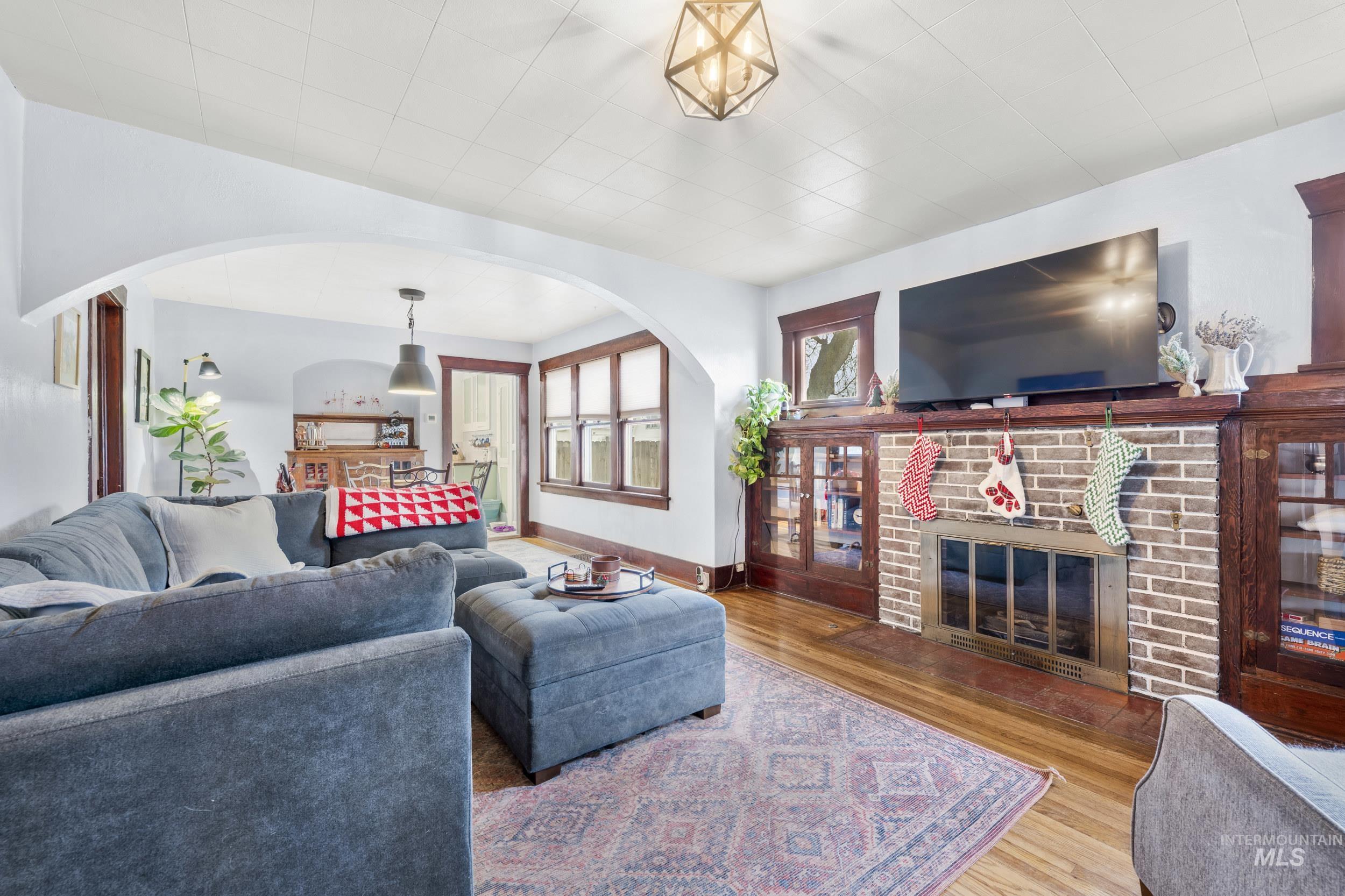 Living area featuring arched walkways, wood finished floors, and a brick fireplace