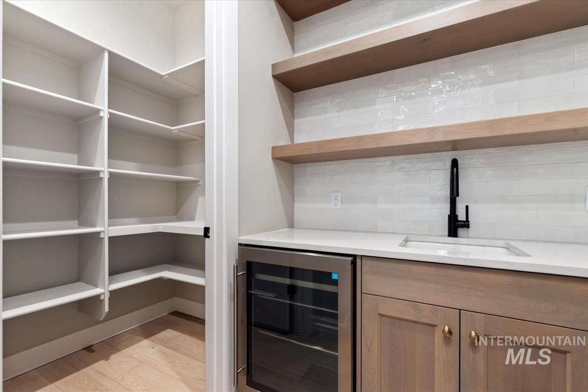 Indoor wet bar featuring wine cooler and light wood-style flooring