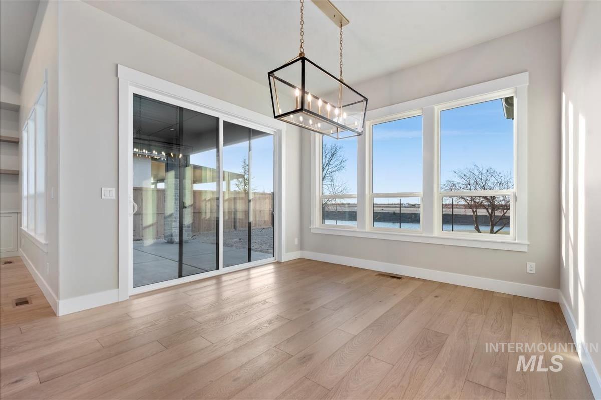 Unfurnished dining area featuring a water view, light wood-style floors, healthy amount of natural light, and a chandelier