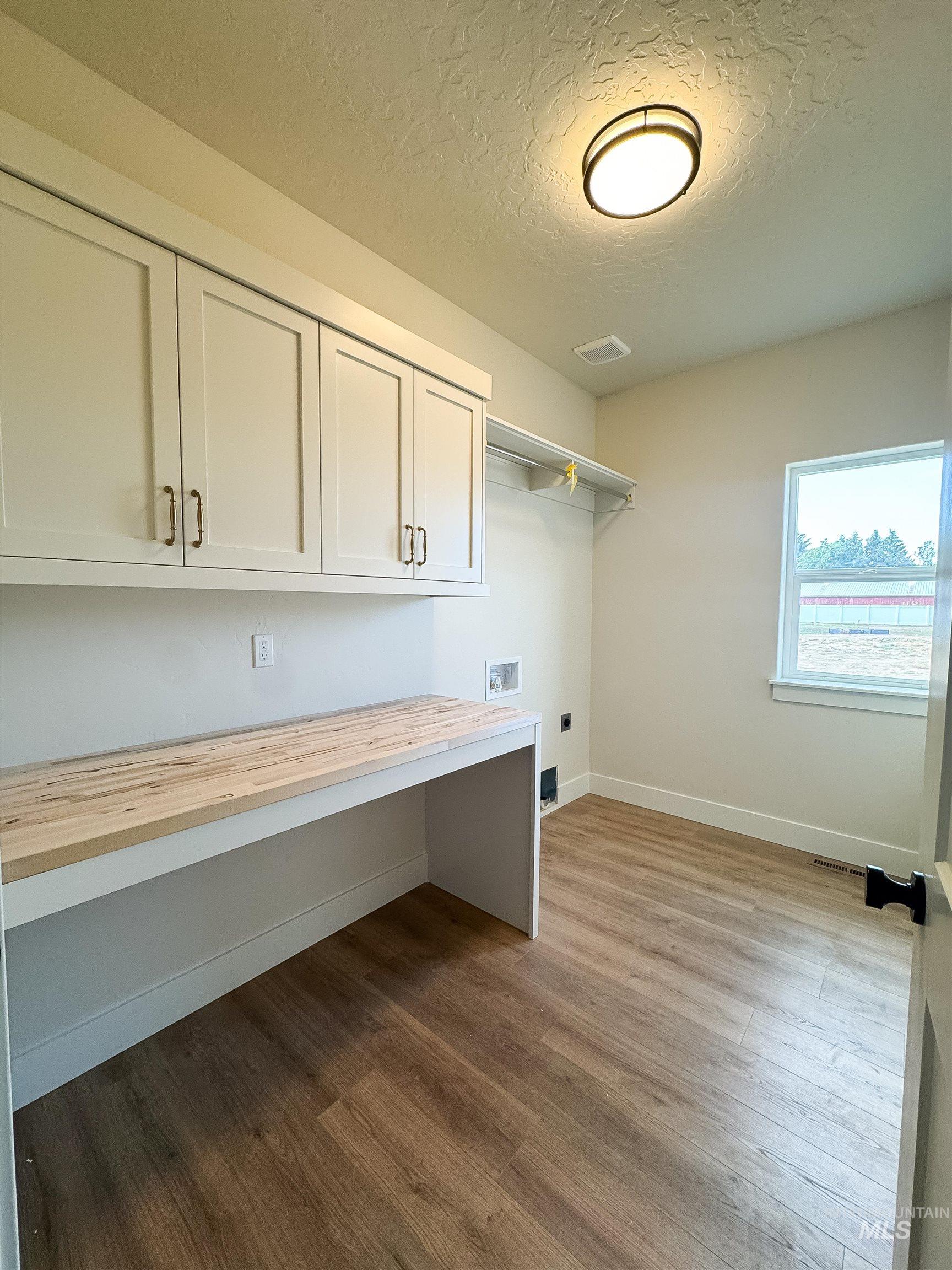 Laundry room featuring electric dryer hookup, cabinet space, a textured ceiling, dark wood-style floors, and hookup for a washing machine