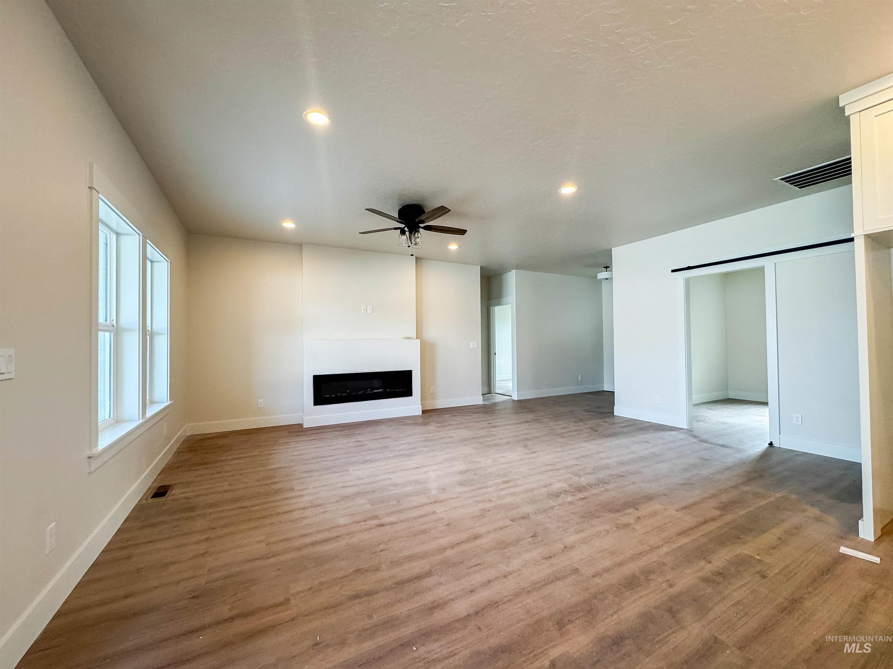 Unfurnished living room with ceiling fan, light wood finished floors, a fireplace, and recessed lighting