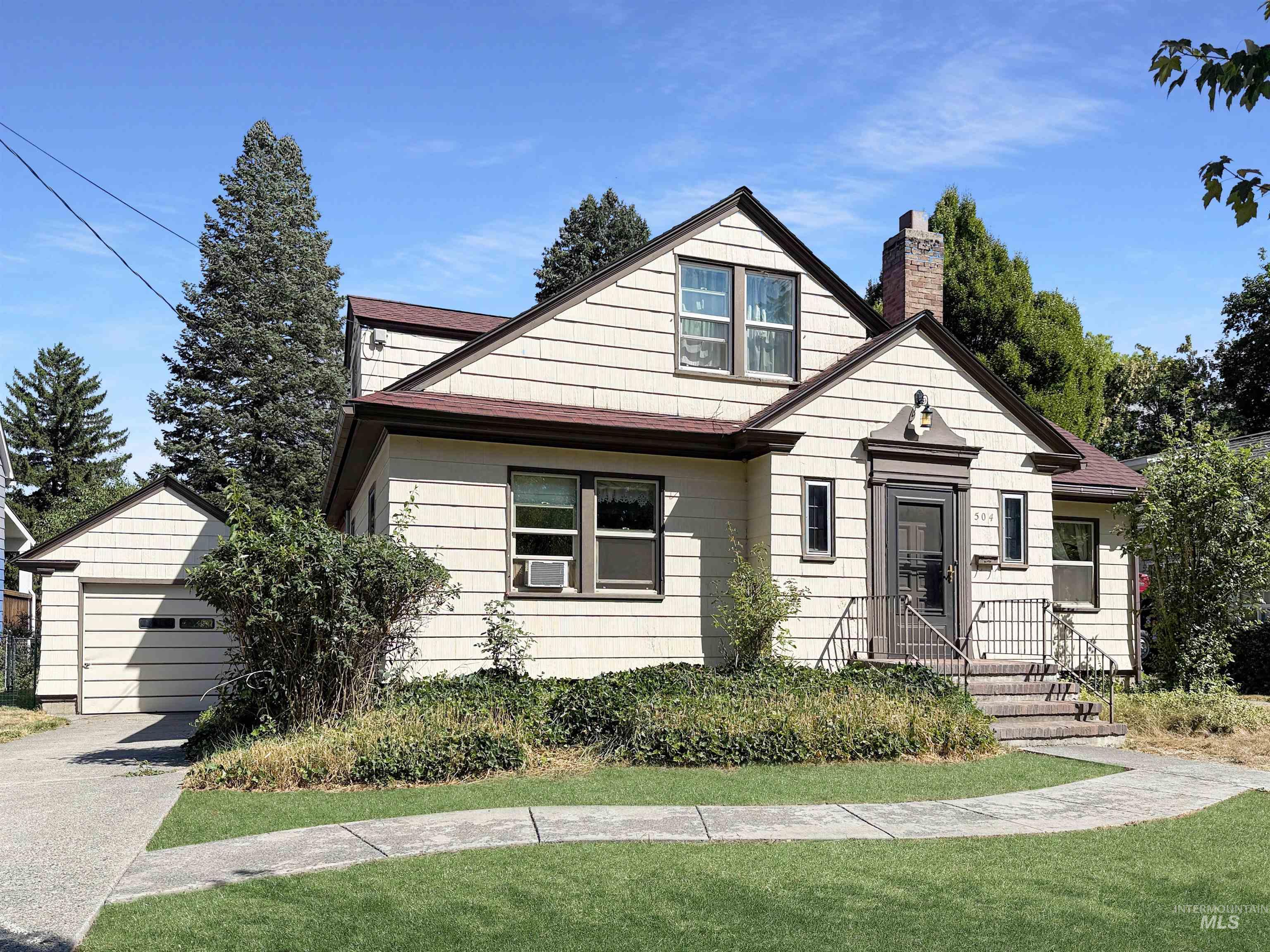 View of front of house featuring an outdoor structure, a chimney, and a front yard