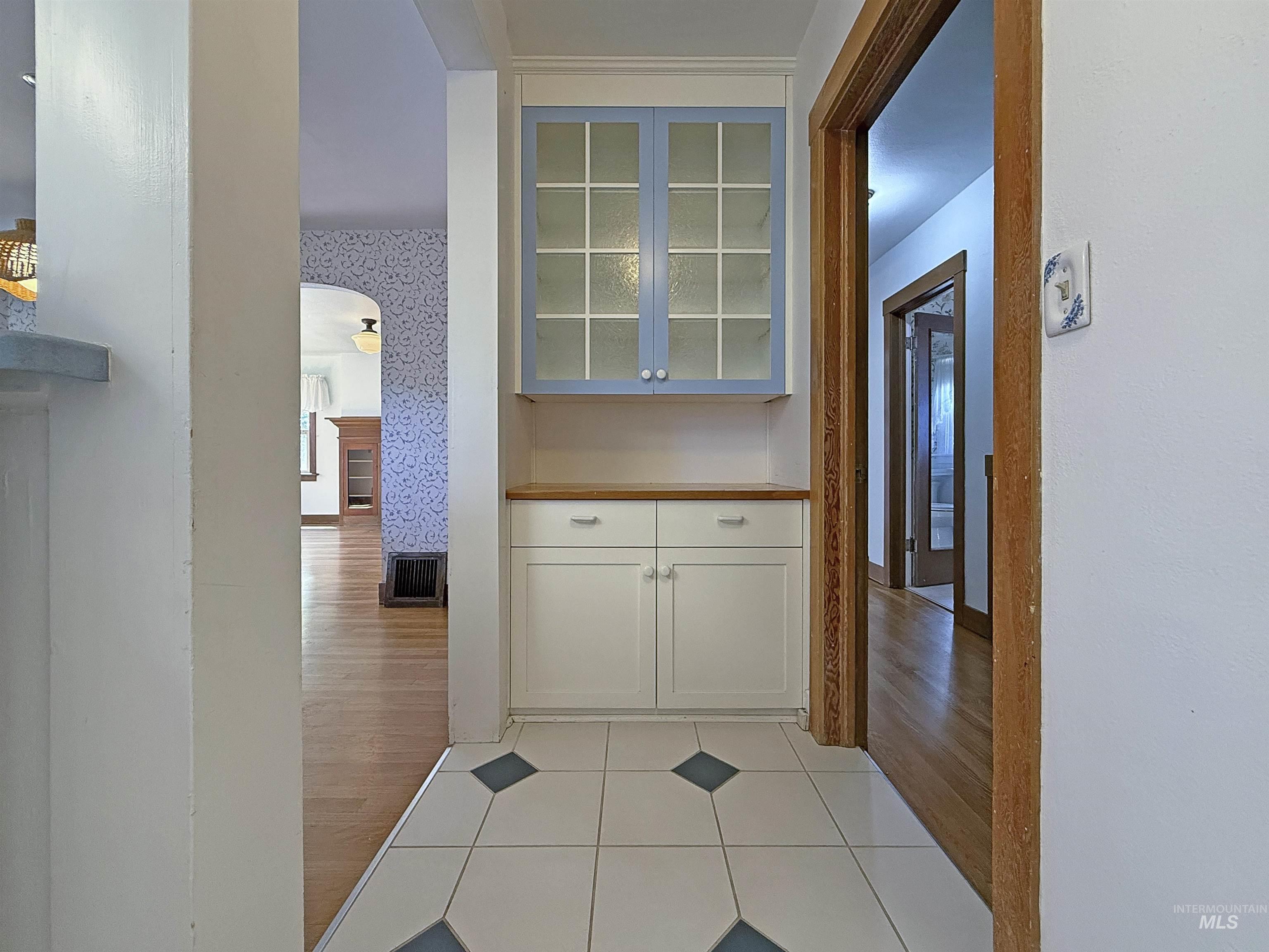 Hall featuring arched walkways and light wood-type flooring