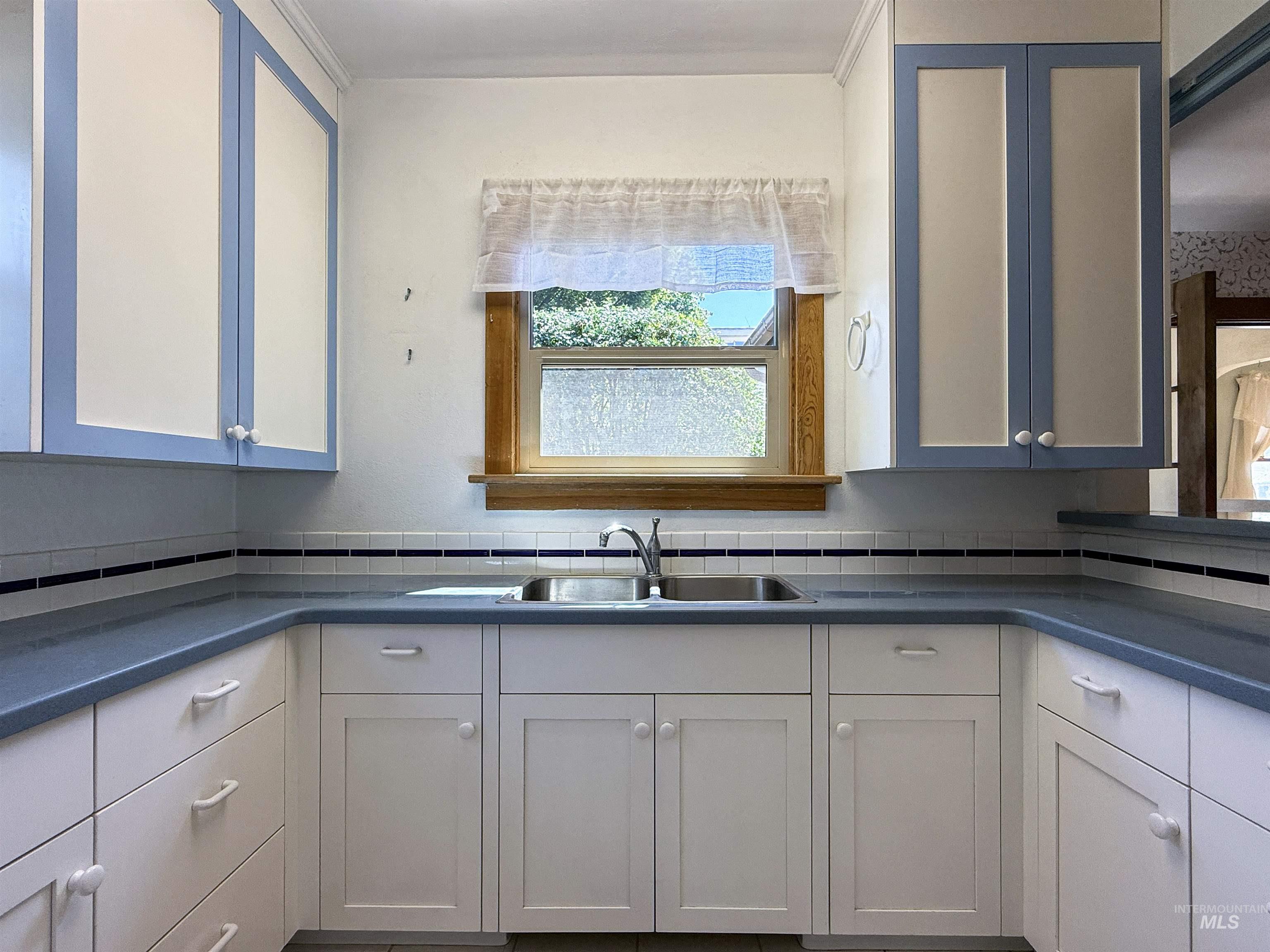 Kitchen with dark countertops, white cabinets, and backsplash