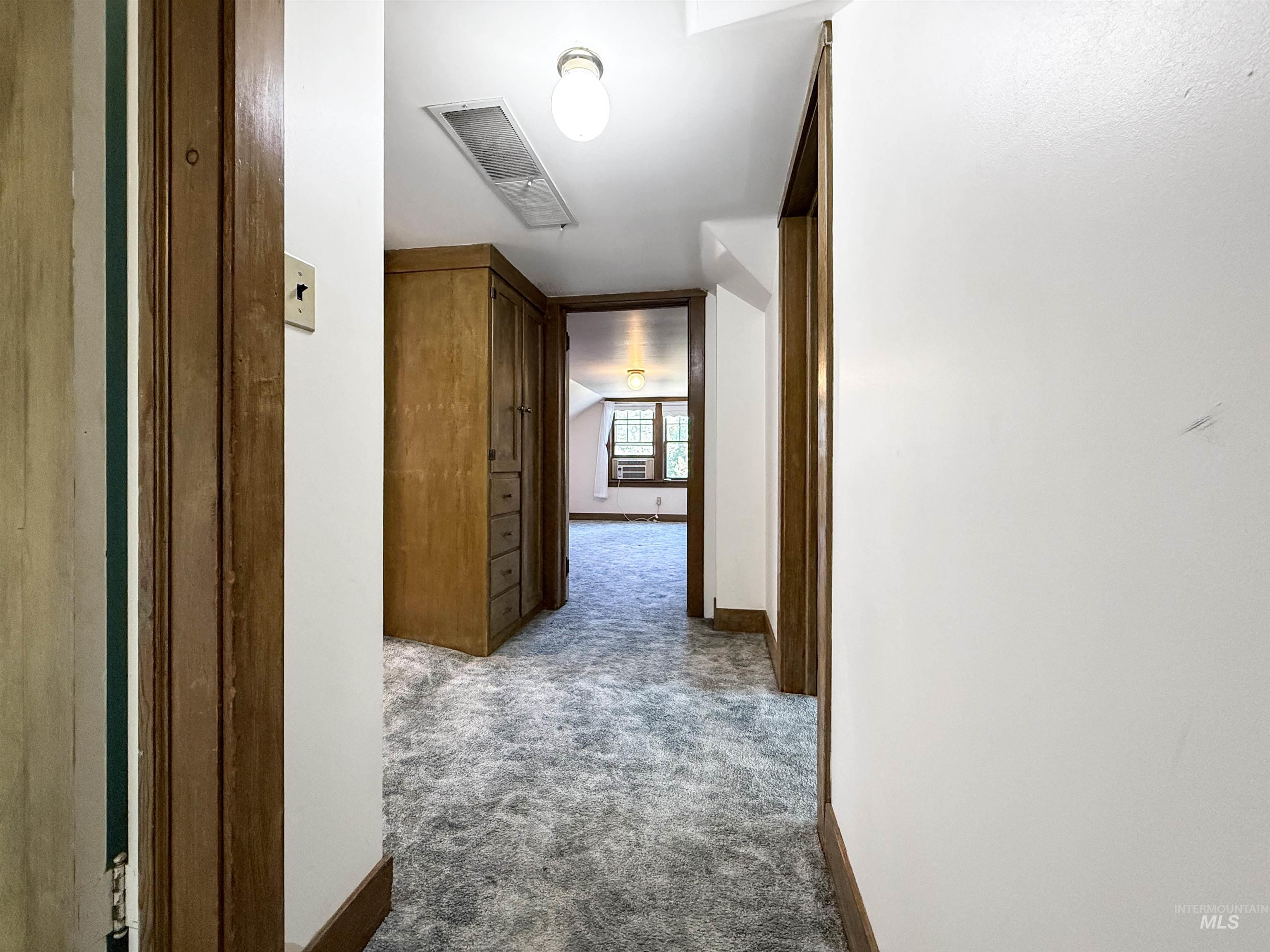 Corridor featuring dark carpet and baseboards