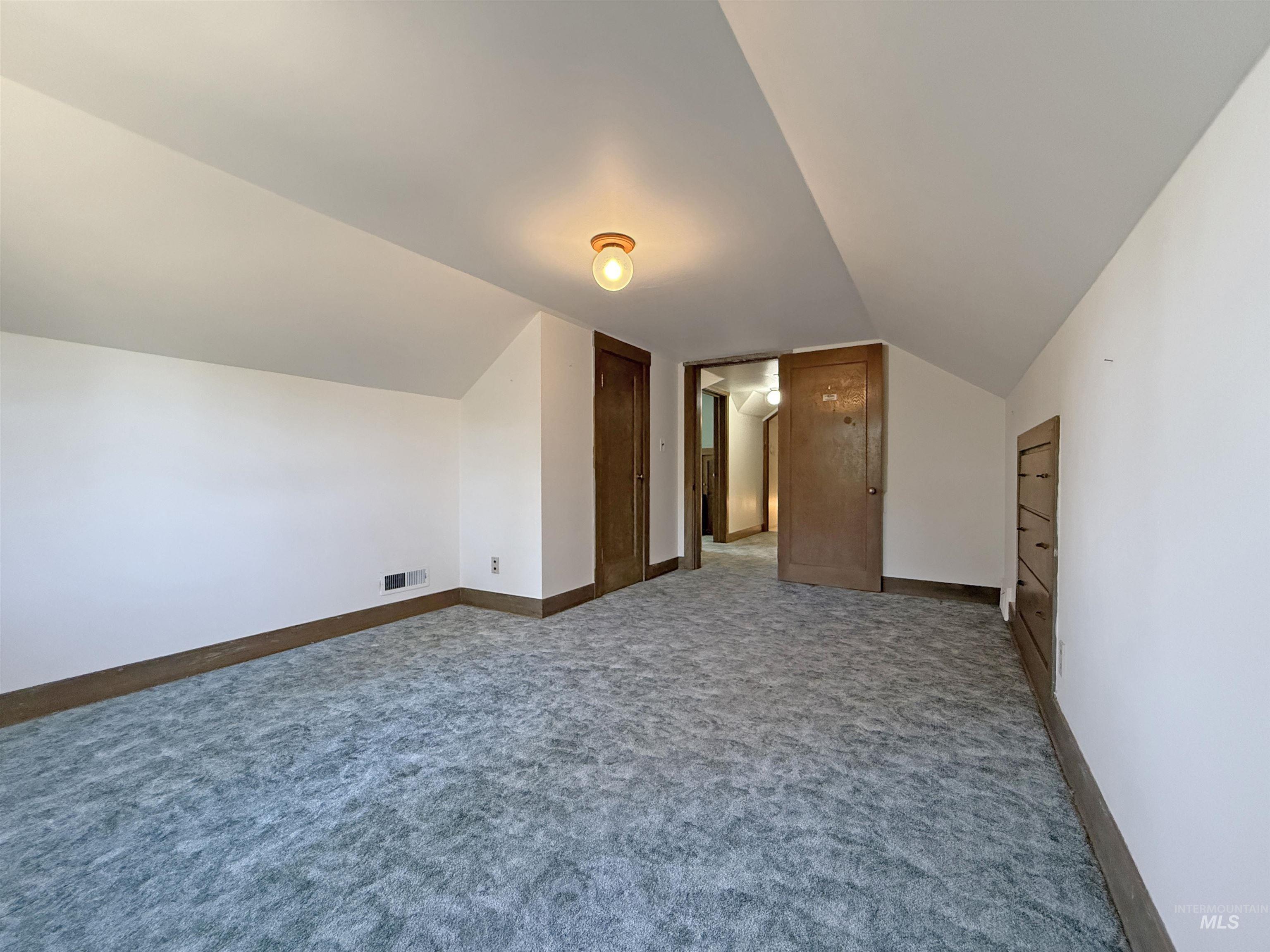 Additional living space with carpet floors and vaulted ceiling