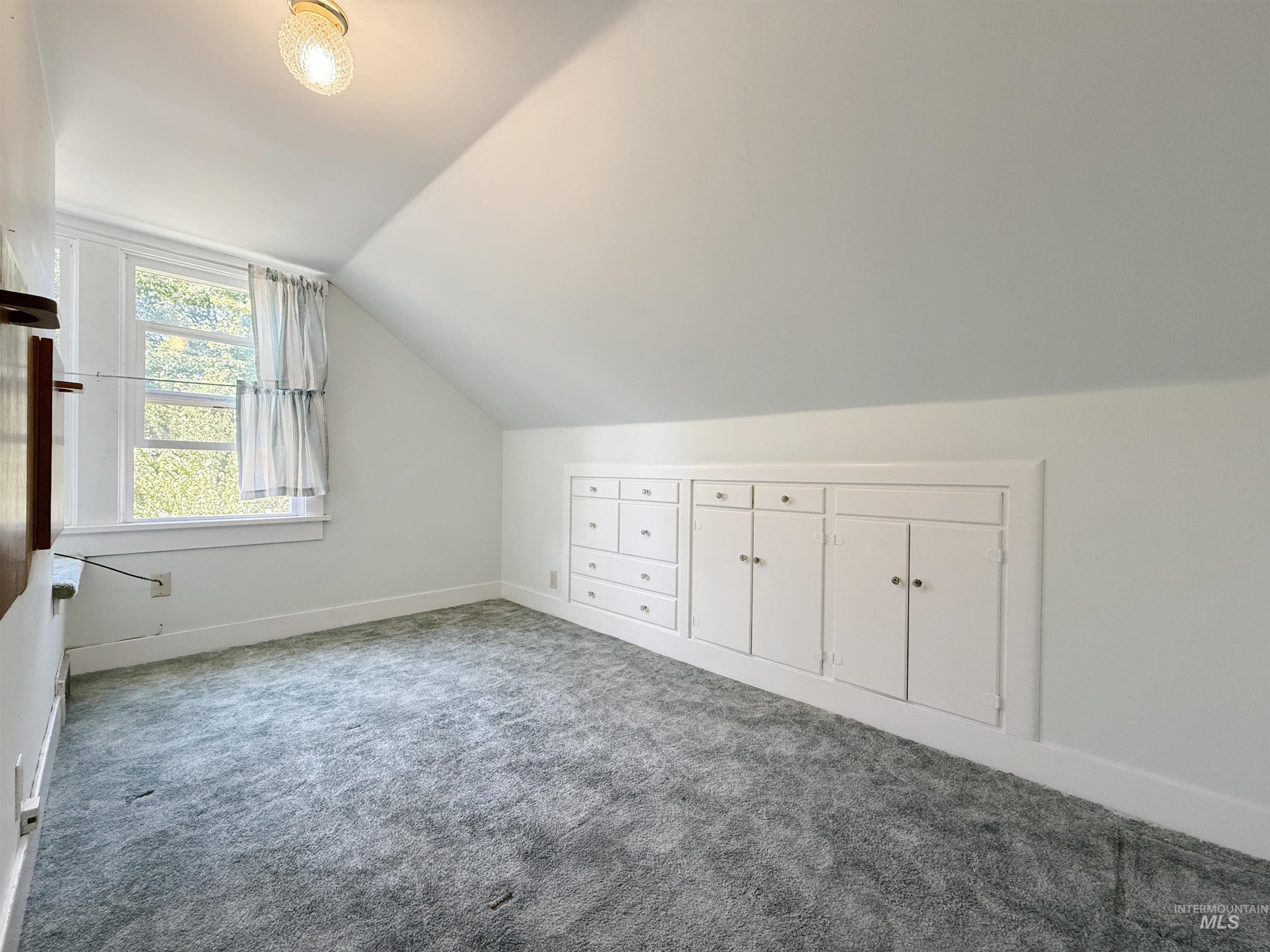 Additional living space with vaulted ceiling and carpet floors