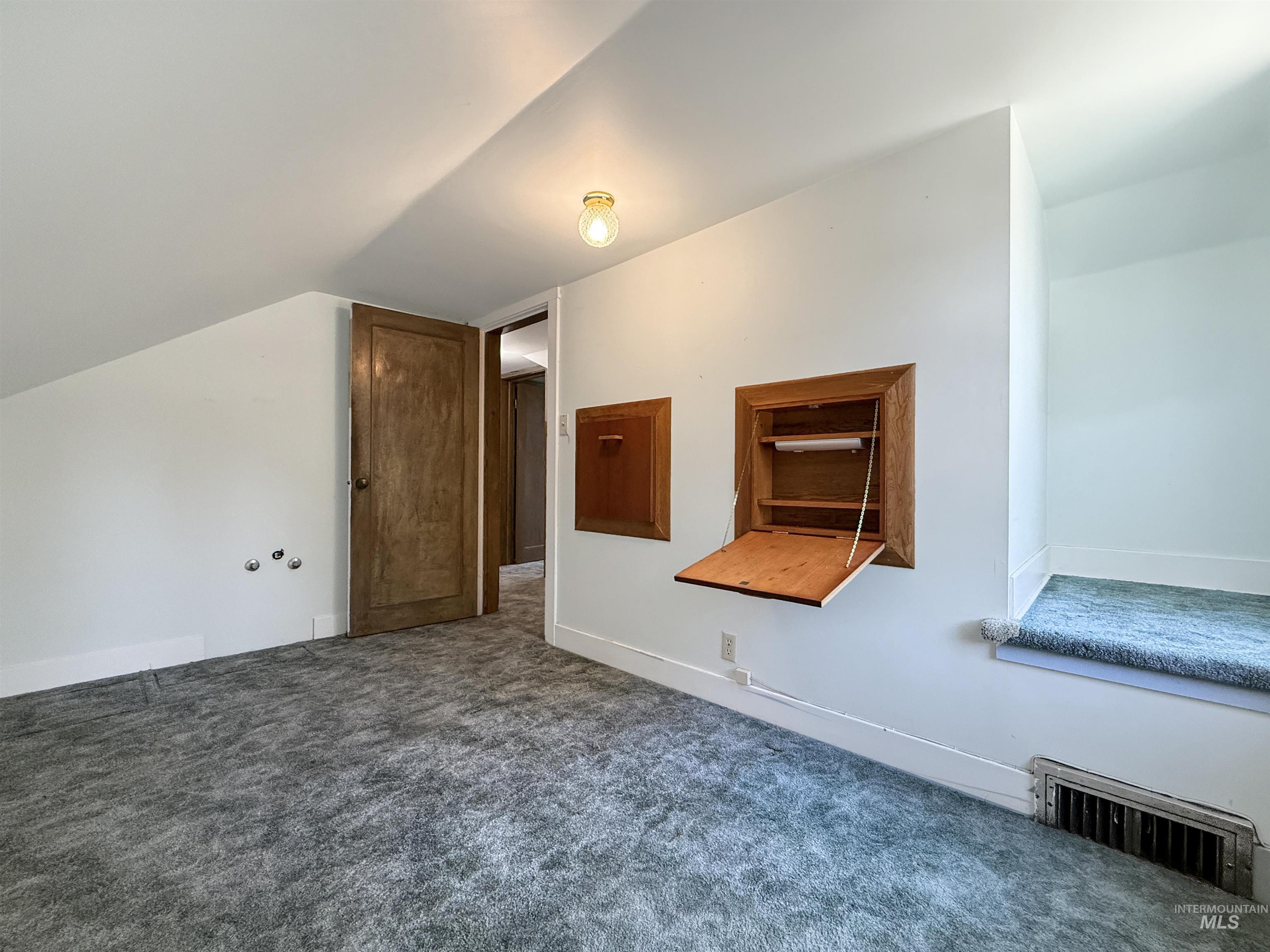 Bonus room featuring dark carpet and baseboards