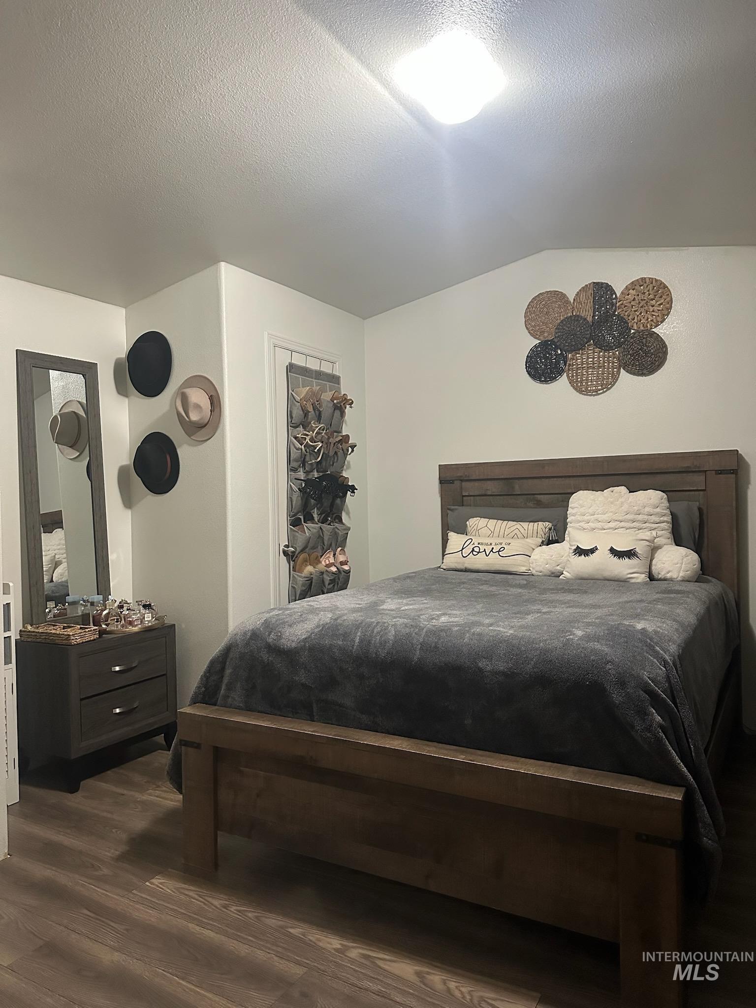 Bedroom featuring a textured ceiling, dark wood-type flooring, and lofted ceiling