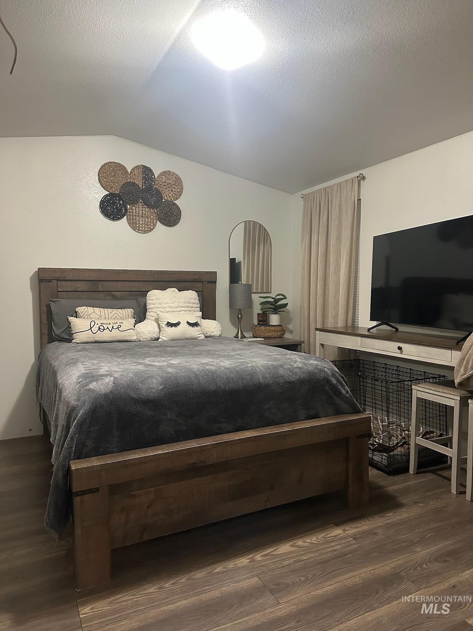 Bedroom with vaulted ceiling, dark wood-style floors, and a textured ceiling
