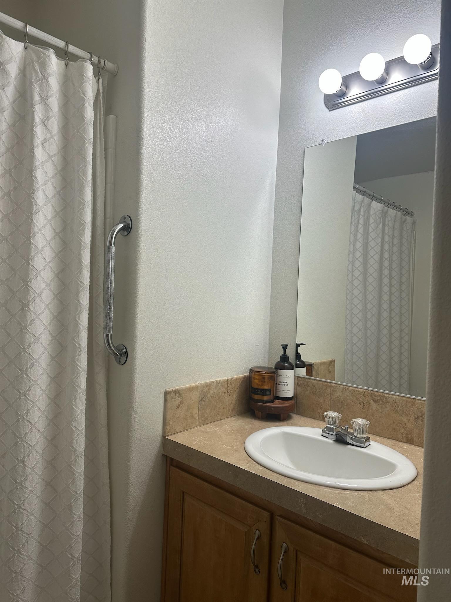Bathroom featuring curtained shower, vanity, and a textured wall