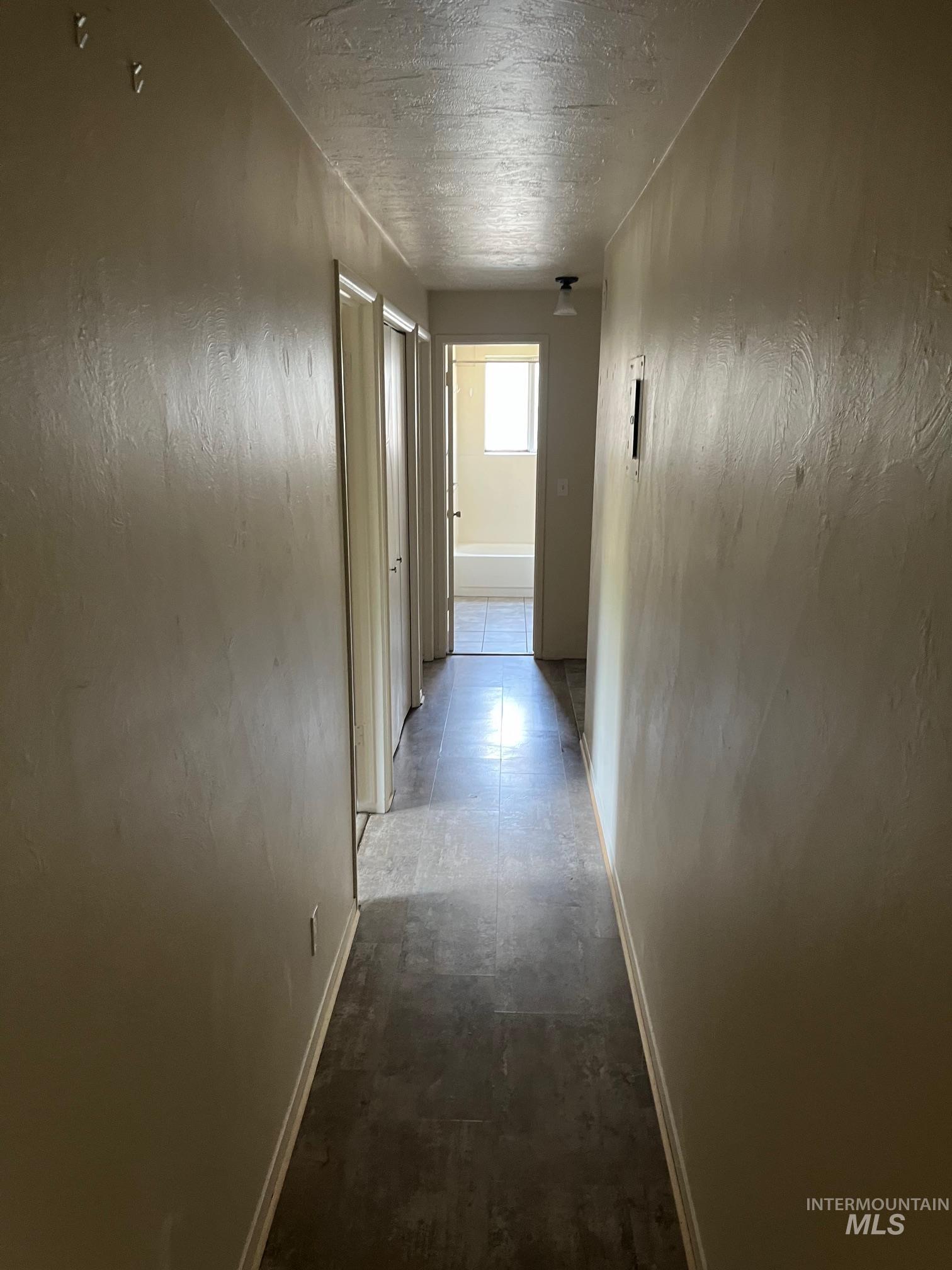 Hall featuring baseboards and a textured ceiling