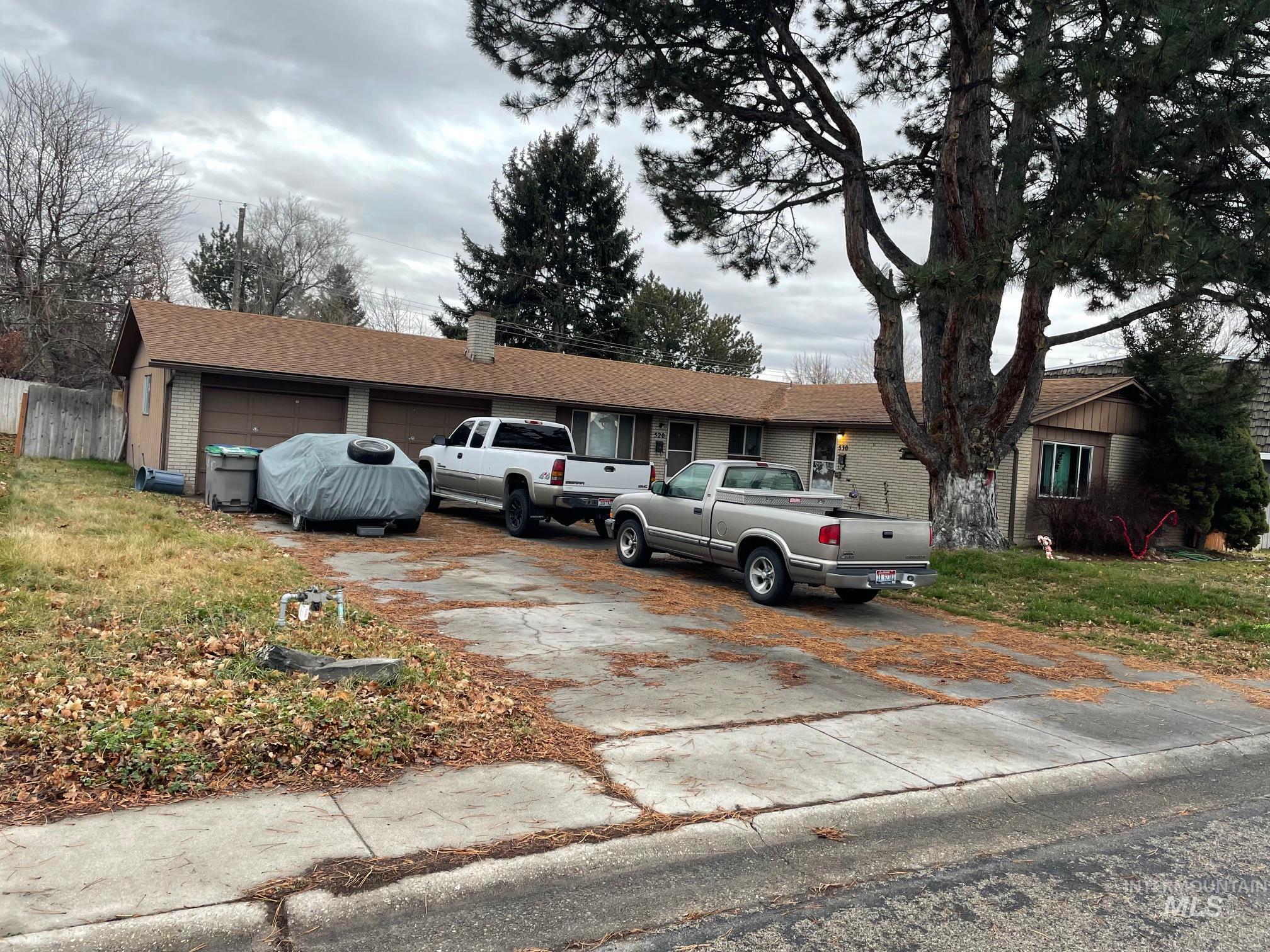 Ranch-style house featuring driveway, a chimney, brick siding, and a front yard