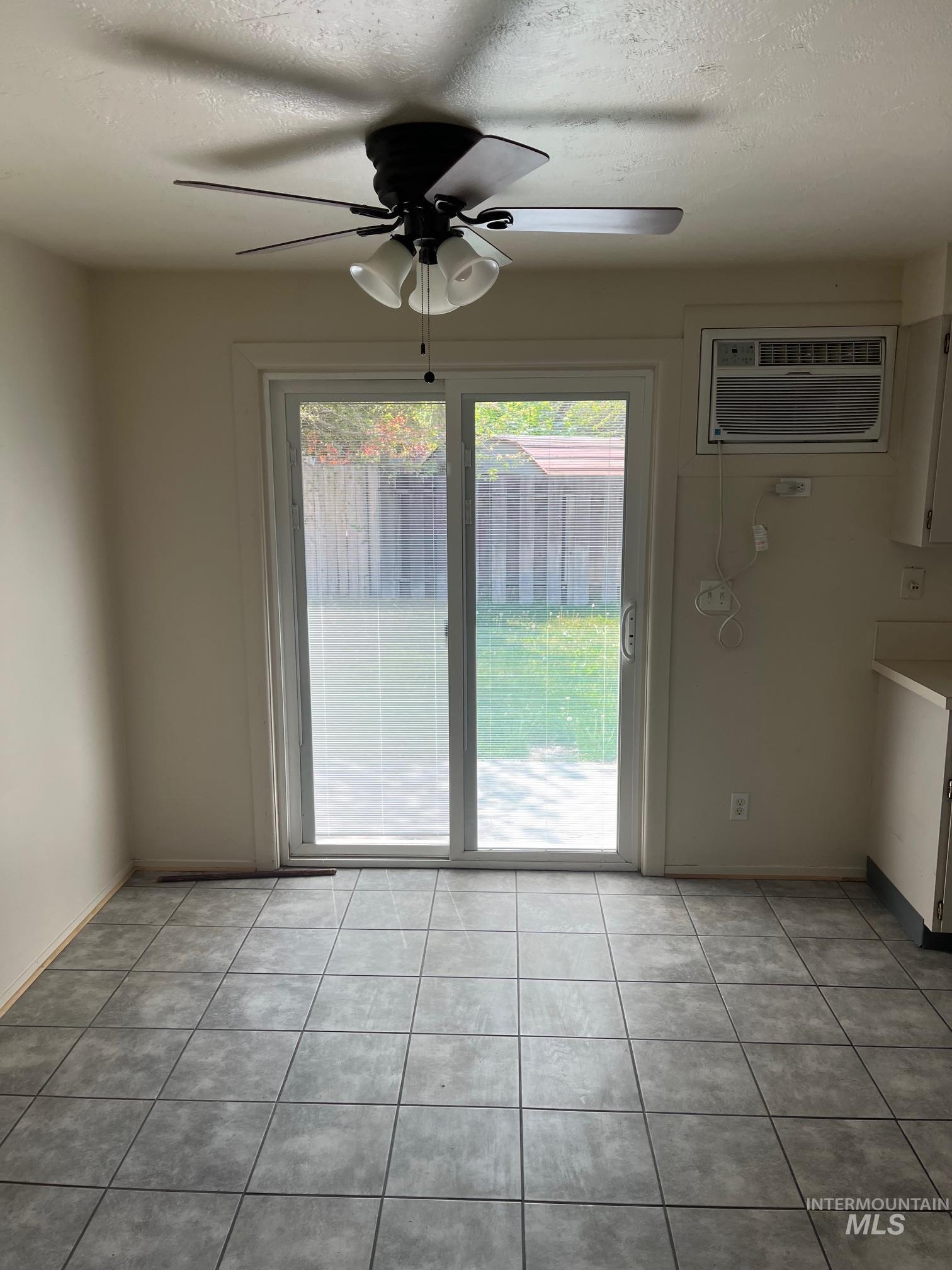 Unfurnished dining area with plenty of natural light, a ceiling fan, a textured ceiling, an AC wall unit, and light tile patterned flooring
