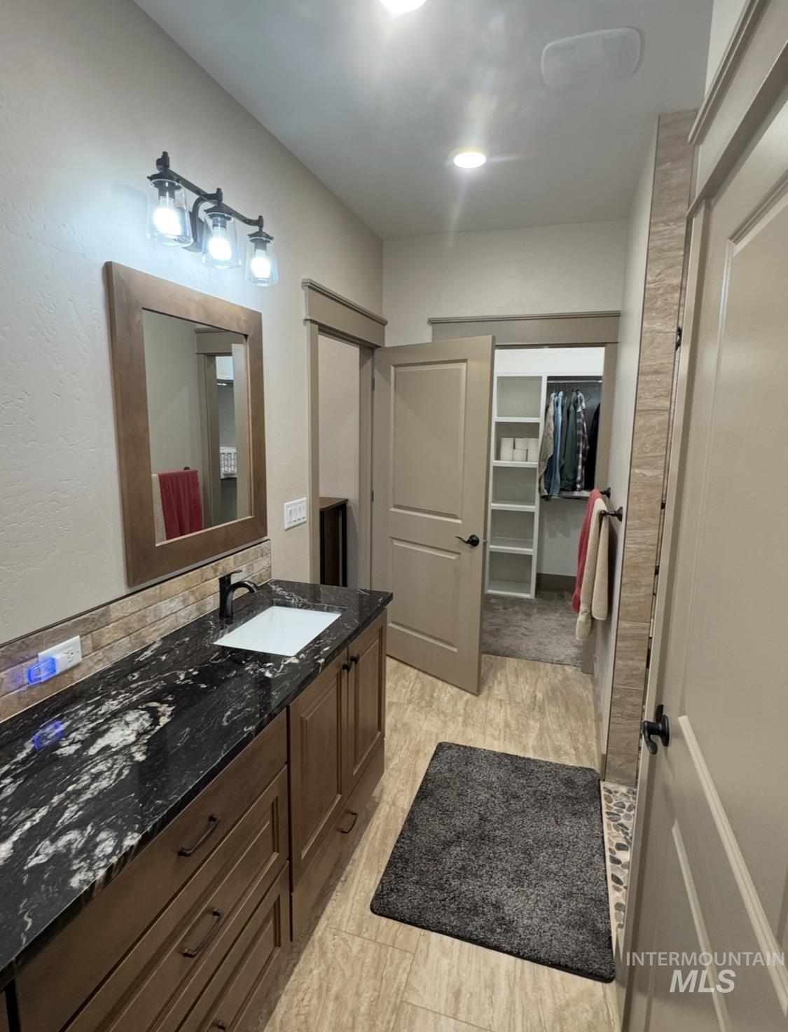 Full bath with a spacious closet, vanity, and decorative backsplash