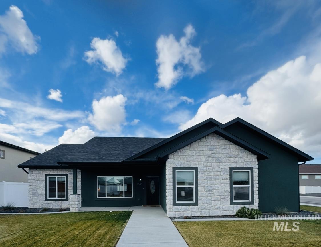 View of front of home featuring stone siding, roof with shingles, and covered porch