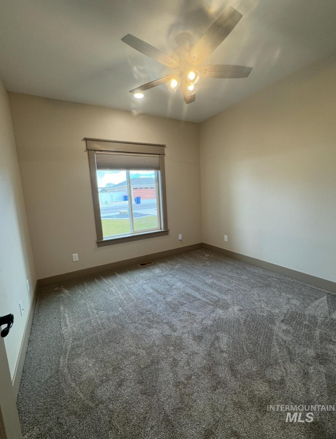 Carpeted spare room featuring baseboards and ceiling fan