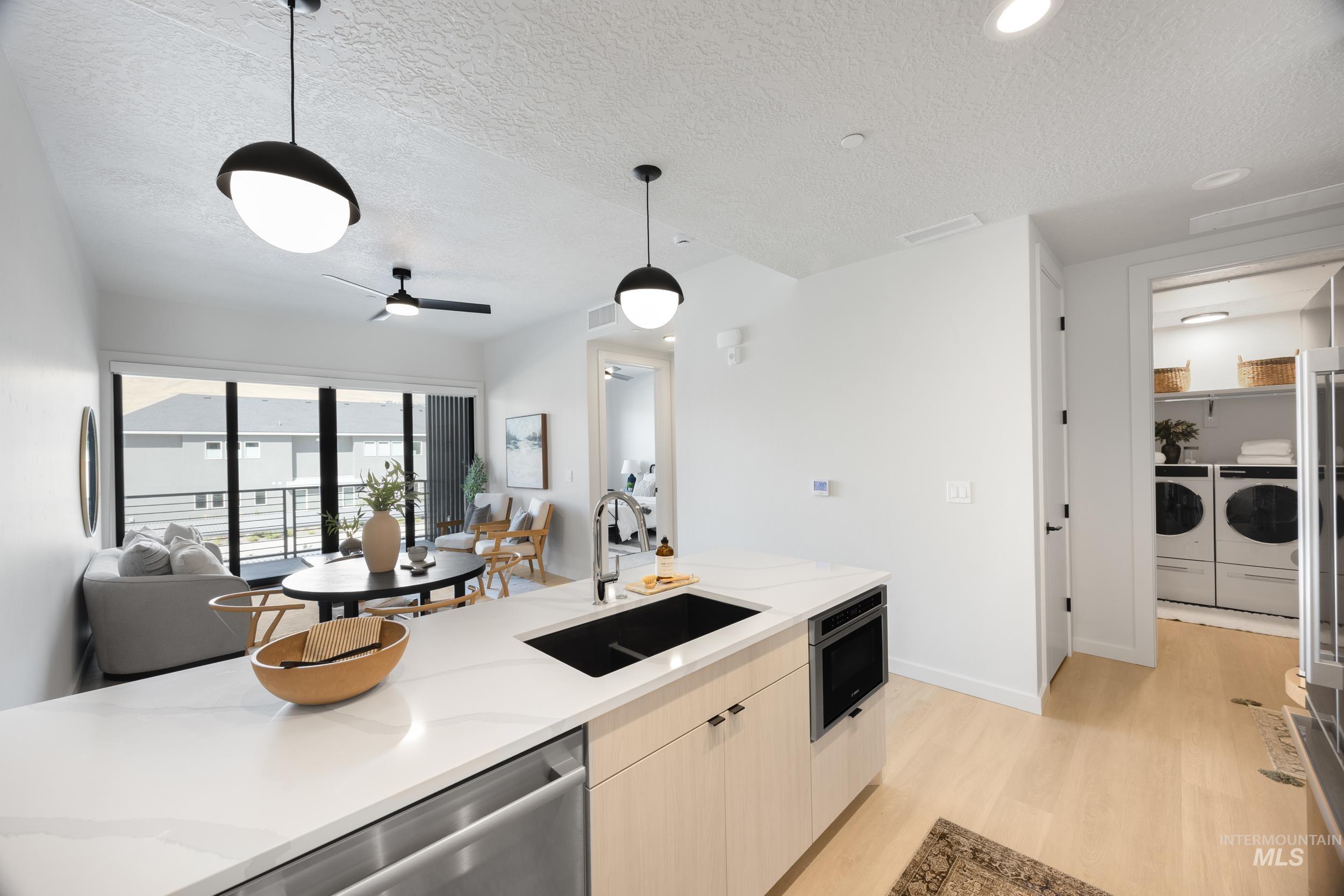 Kitchen featuring separate washer and dryer, open floor plan, light wood-type flooring, a textured ceiling, and decorative light fixtures