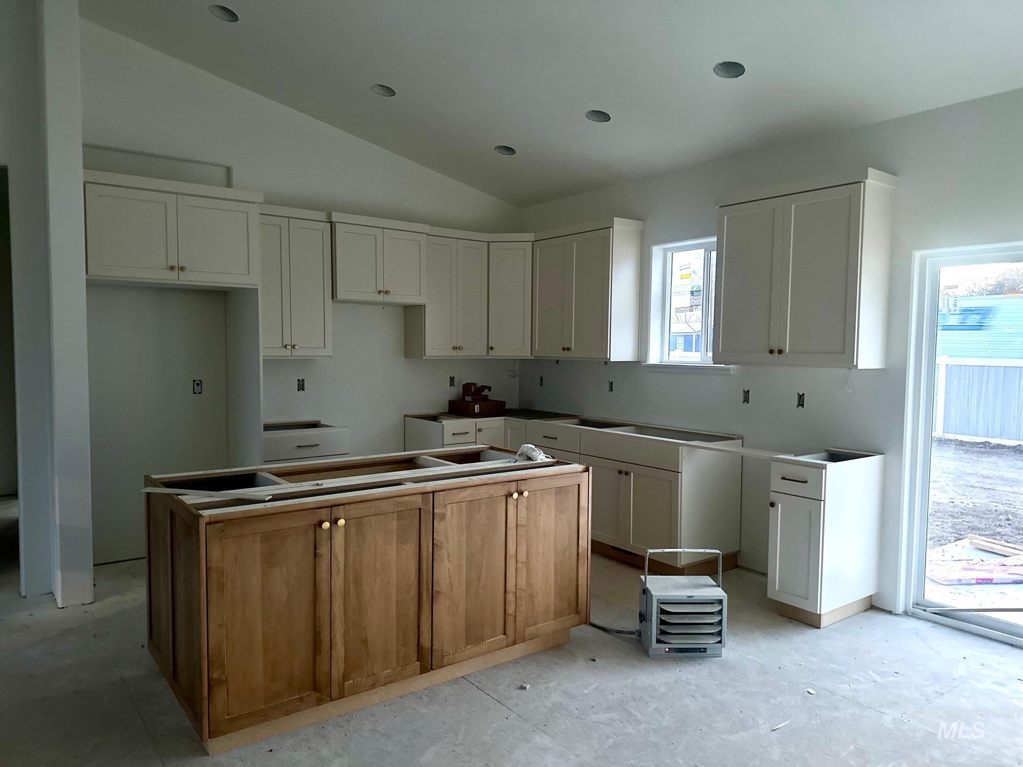 Kitchen with a center island, vaulted ceiling, and white cabinets