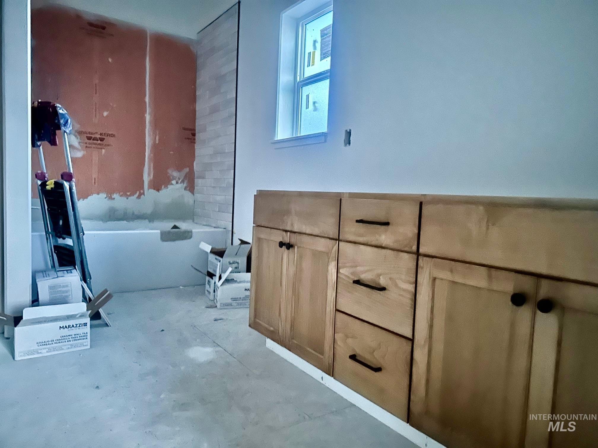 Bathroom with a freestanding tub, unfinished concrete flooring, and vanity