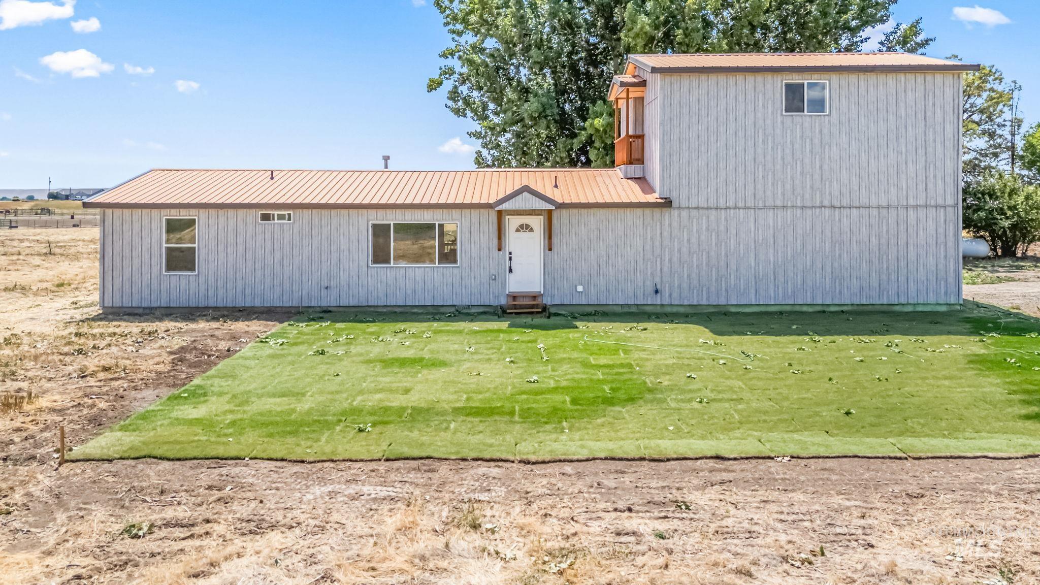 View of front of home with a metal roof and a front lawn