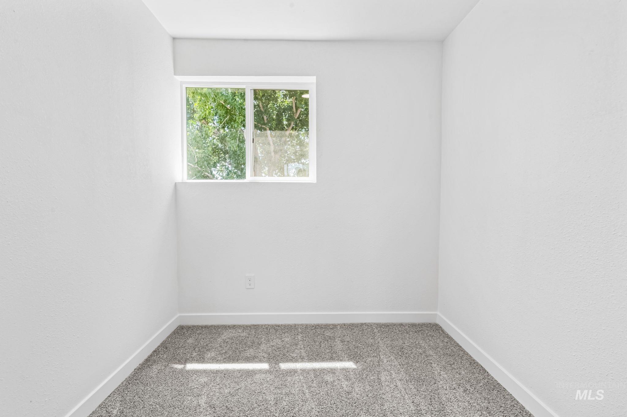 Carpeted spare room featuring baseboards