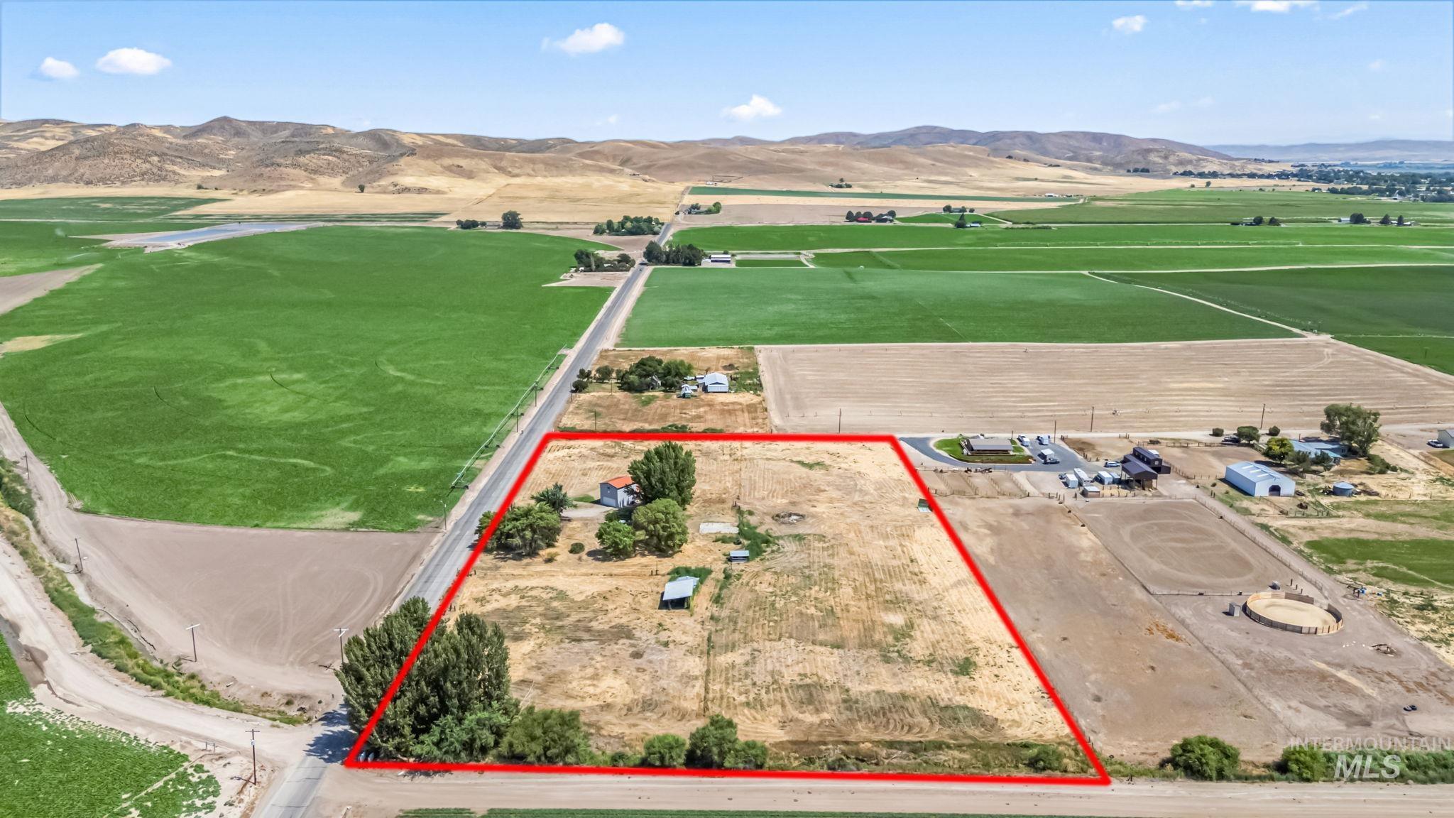 Aerial view of sparsely populated area featuring a mountain backdrop, property boundaries highlighted, and rows of crops