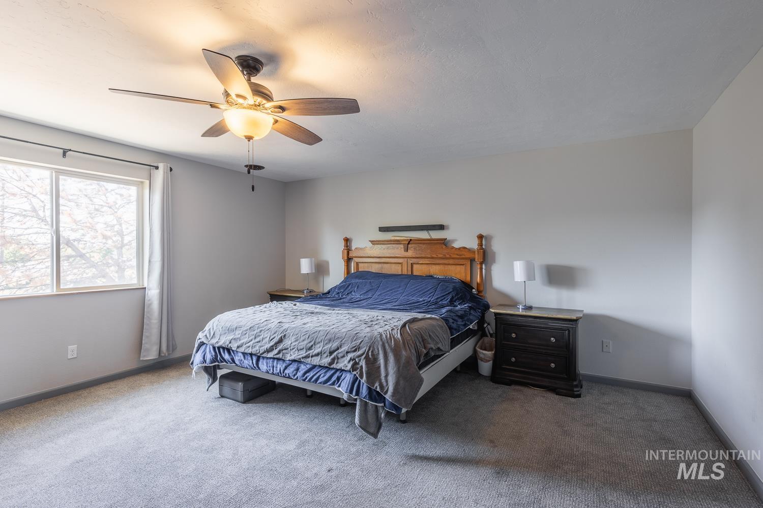 Carpeted bedroom with a ceiling fan and baseboards