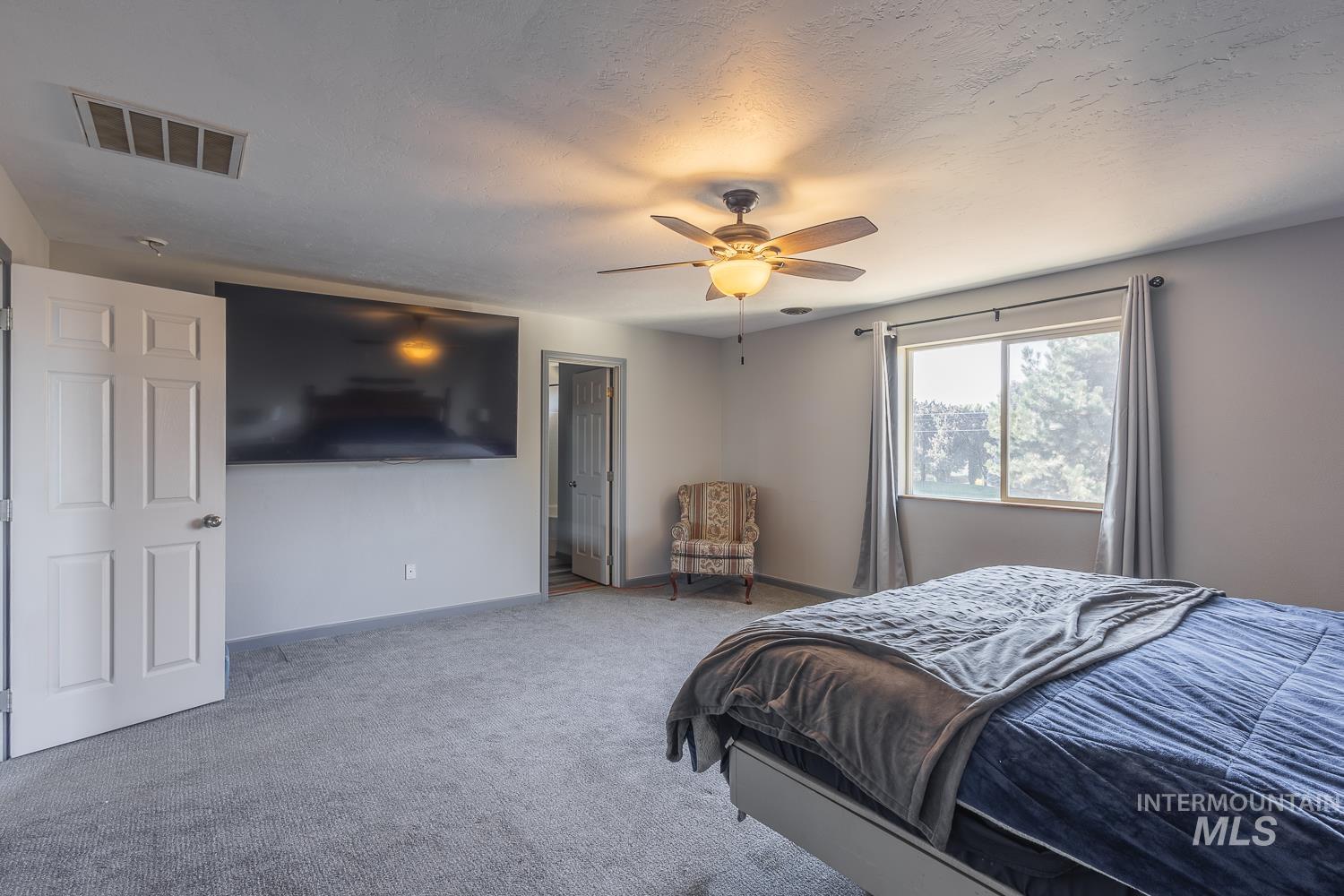 Bedroom featuring carpet flooring, ceiling fan, and a textured ceiling