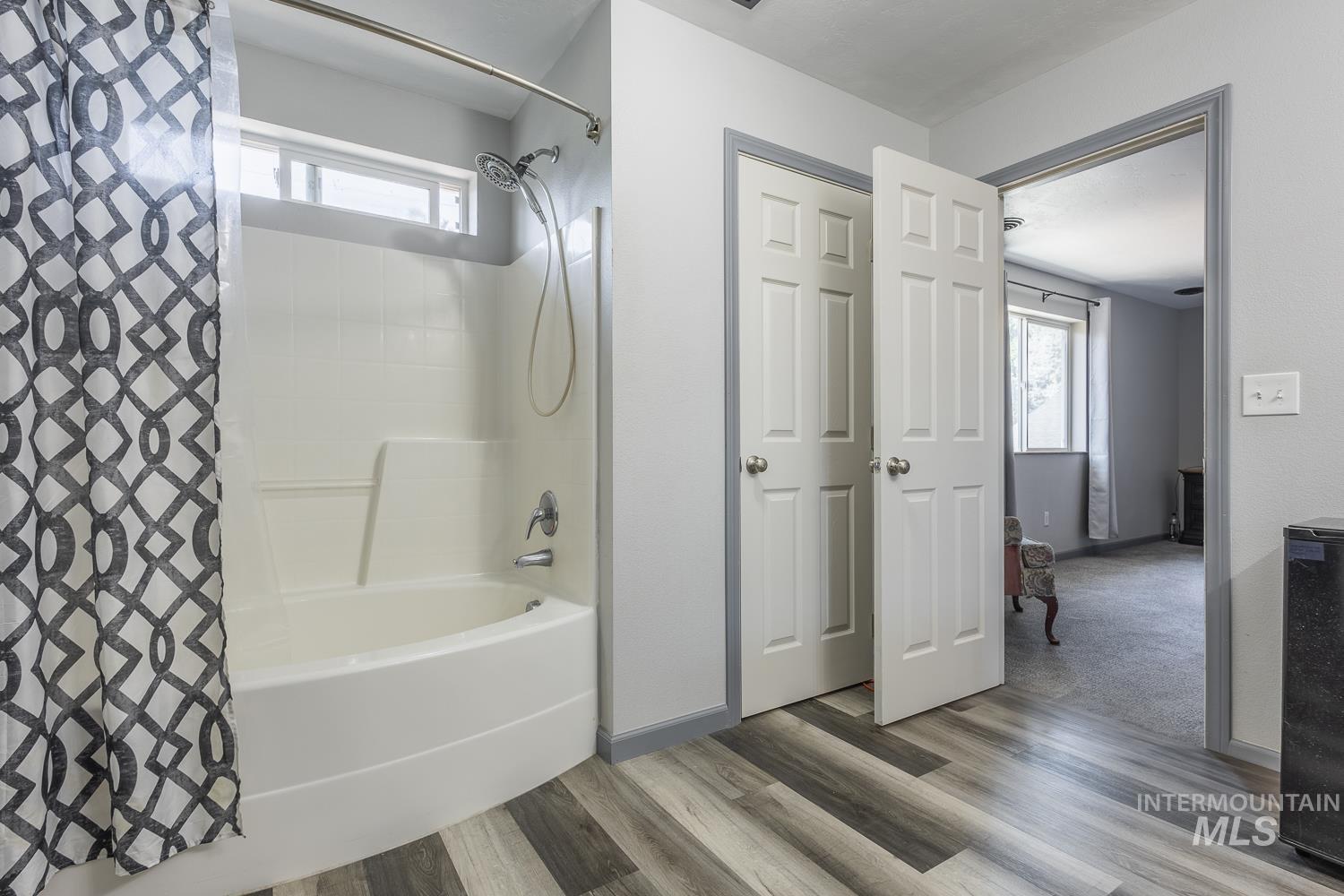 Bathroom with plenty of natural light, shower / bath combo, and light wood-style floors