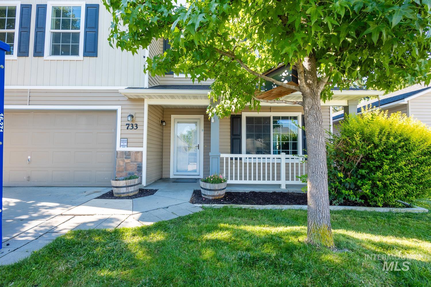 View of front of home with covered porch, a front yard, stone siding, a garage, and board and batten siding
