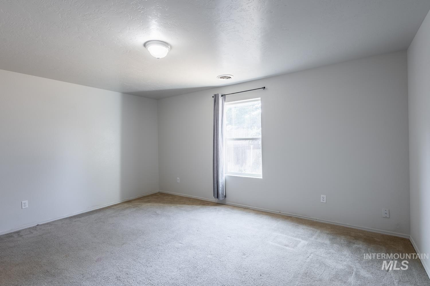 Spare room featuring a textured ceiling and light carpet